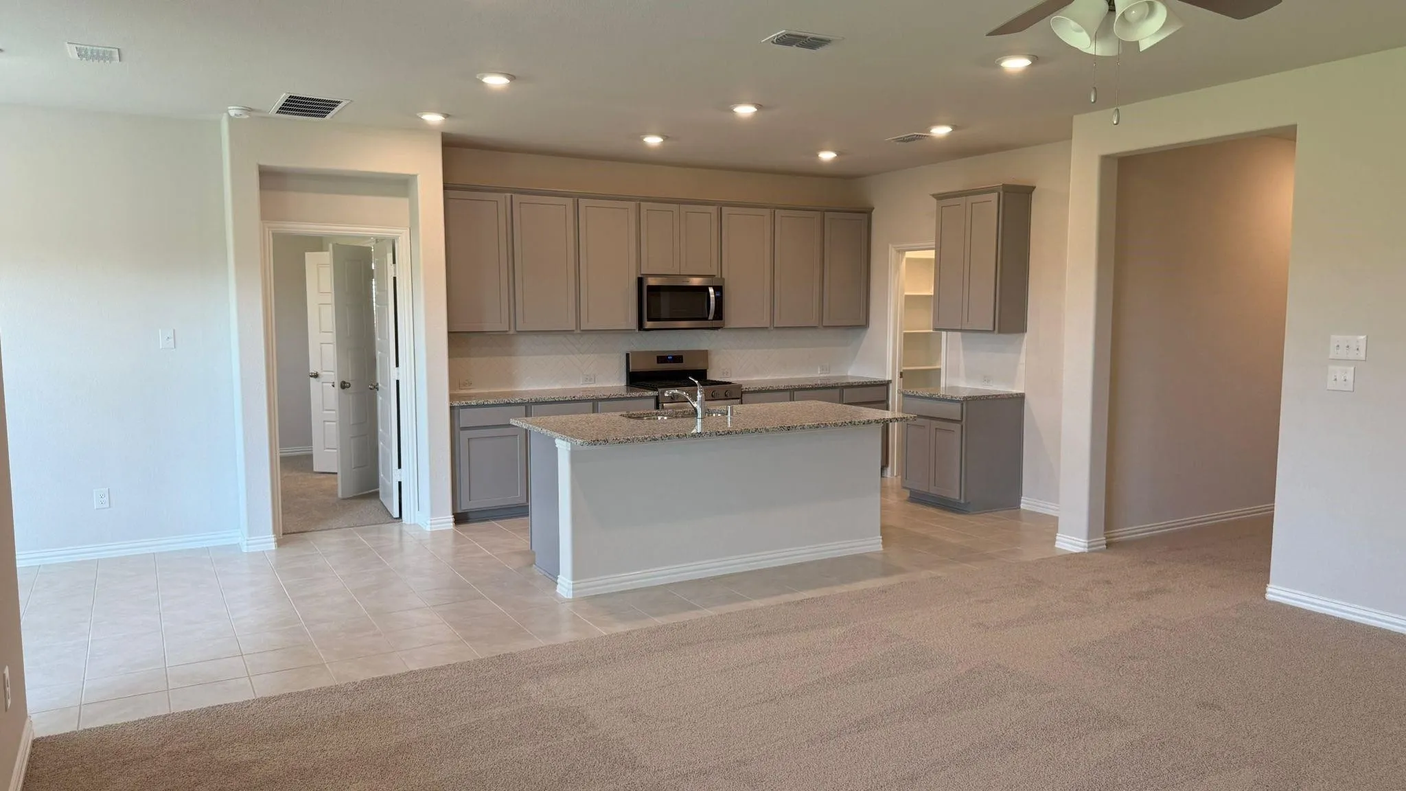 Kitchen featuring gray cabinetry, stainless steel appliances, a center island, and recessed lighting
