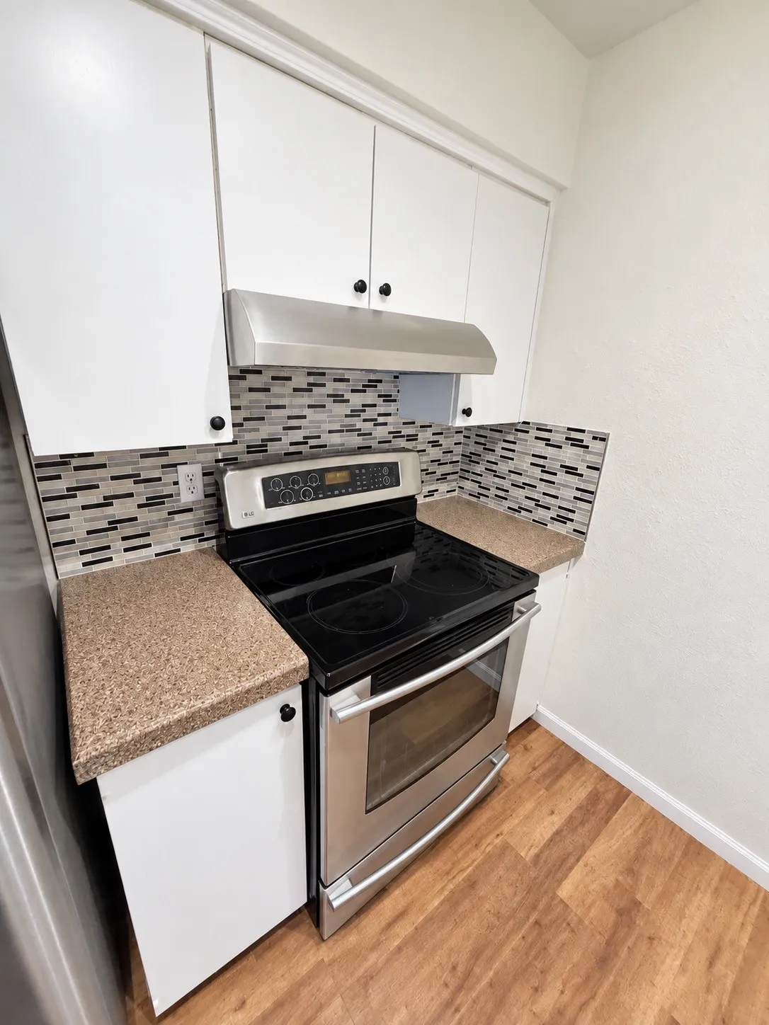 Range and hood with glass tile backsplash.
