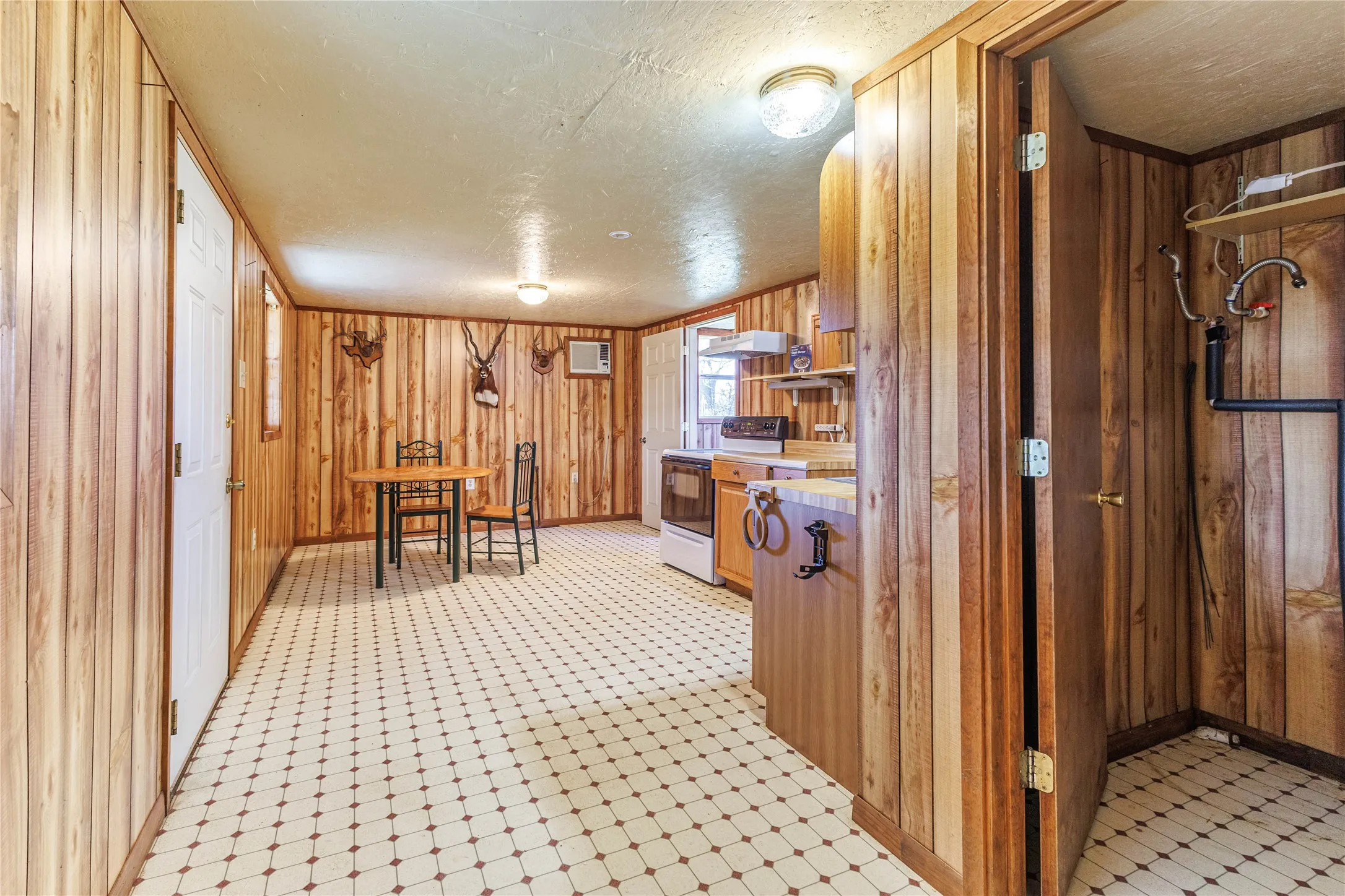 Wood-paneled walls, patterned tile flooring, and integrated kitchen cabinetry
