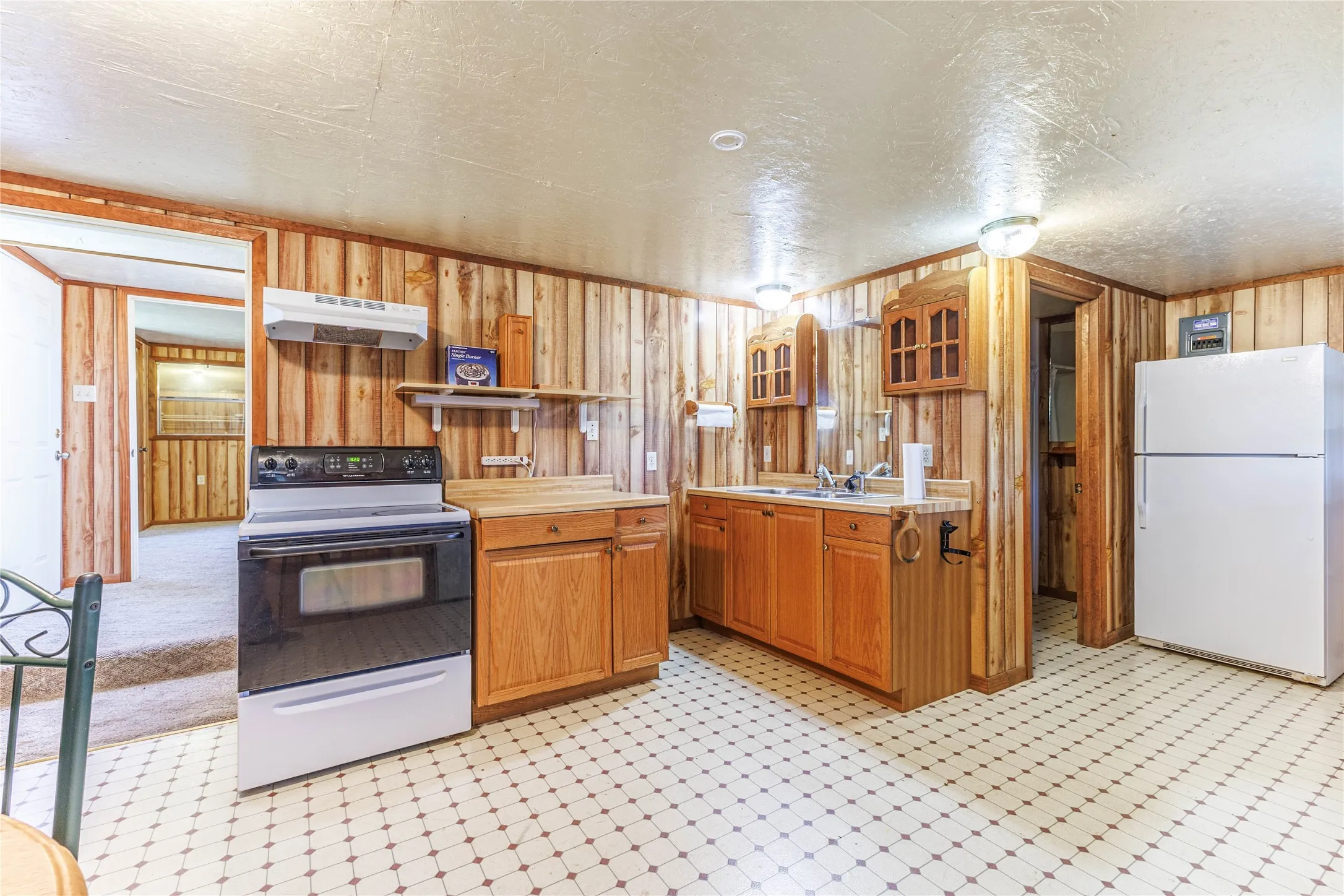Kitchen featuring wood-paneled walls, white appliances, and a patterned tile floor