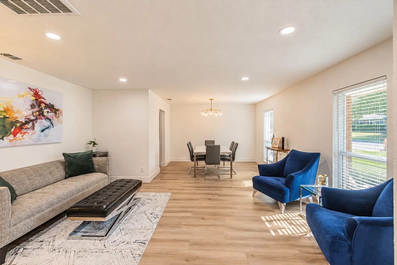 Open-concept living and dining area featuring wood-finish flooring, recessed lighting, and ample natural light through large windows