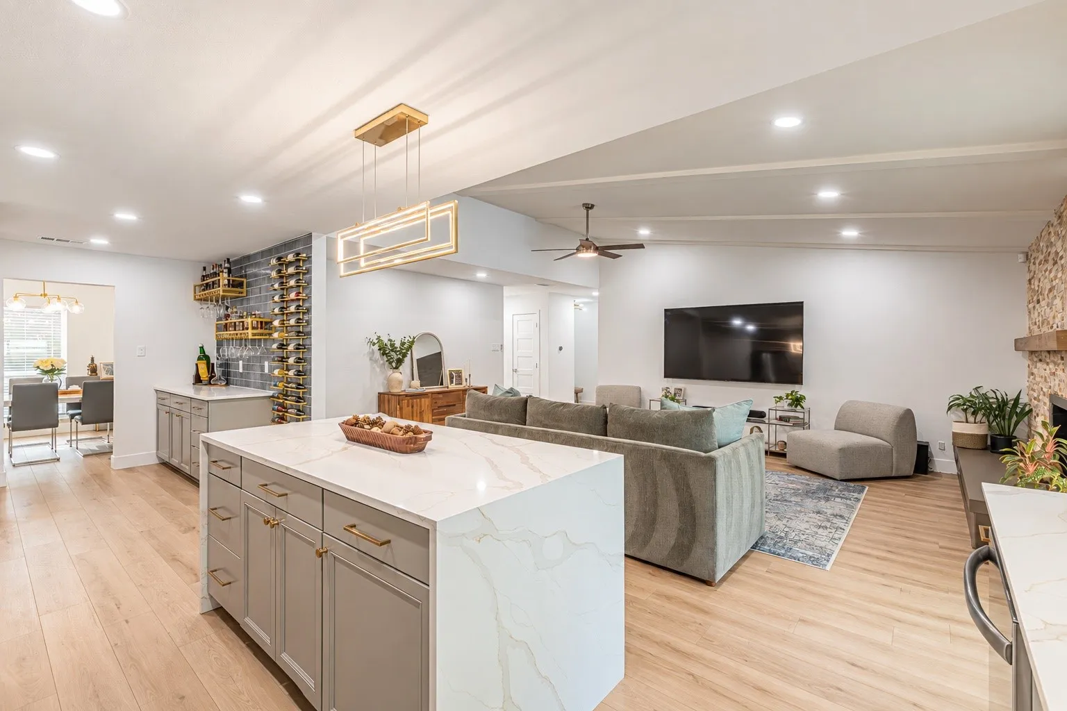 Kitchen island with stone countertop, wood-finish flooring, recessed lighting, and a built-in wine rack with a beverage bar