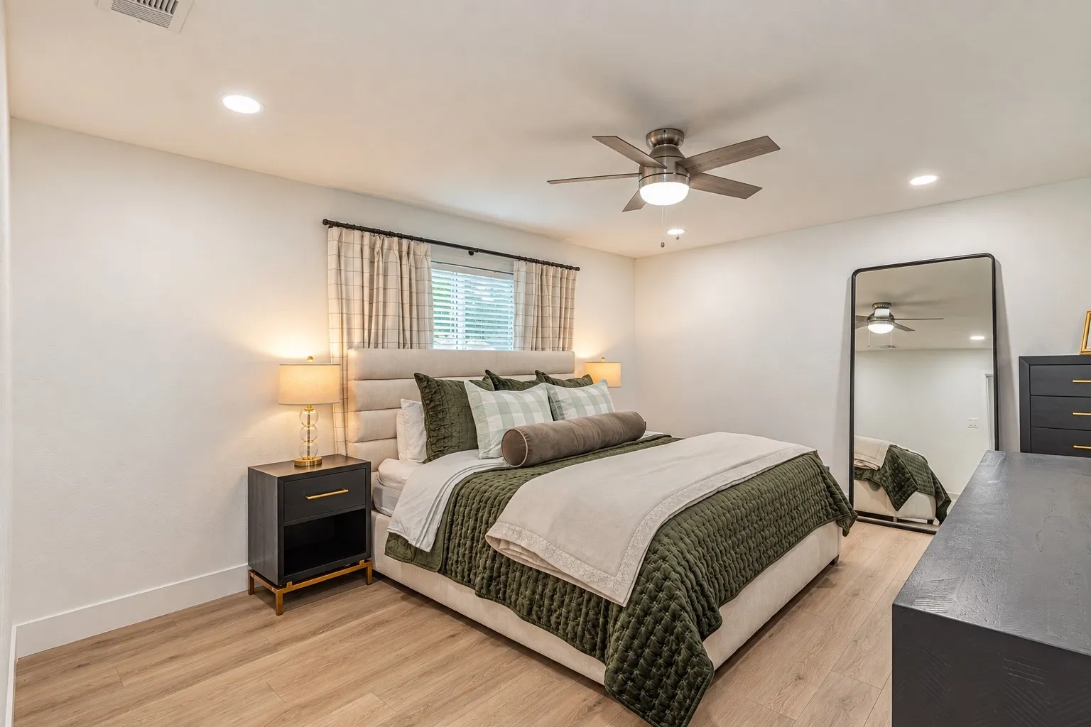 Recessed ceiling lighting, a ceiling fan with integrated light, wood-finish flooring, and window blinds