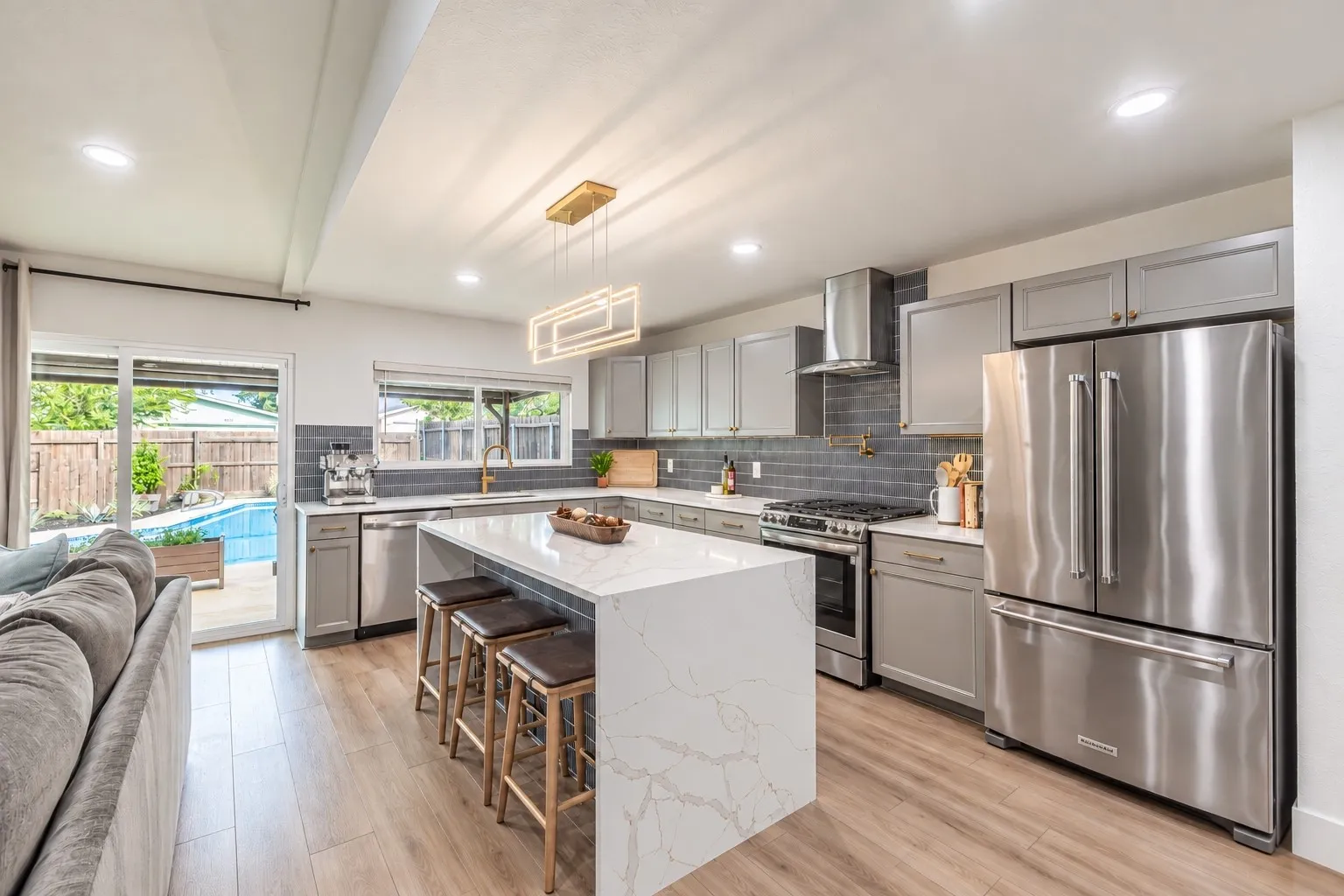 Kitchen with a waterfall-edge island, stainless steel appliances, and wood-finish flooring
