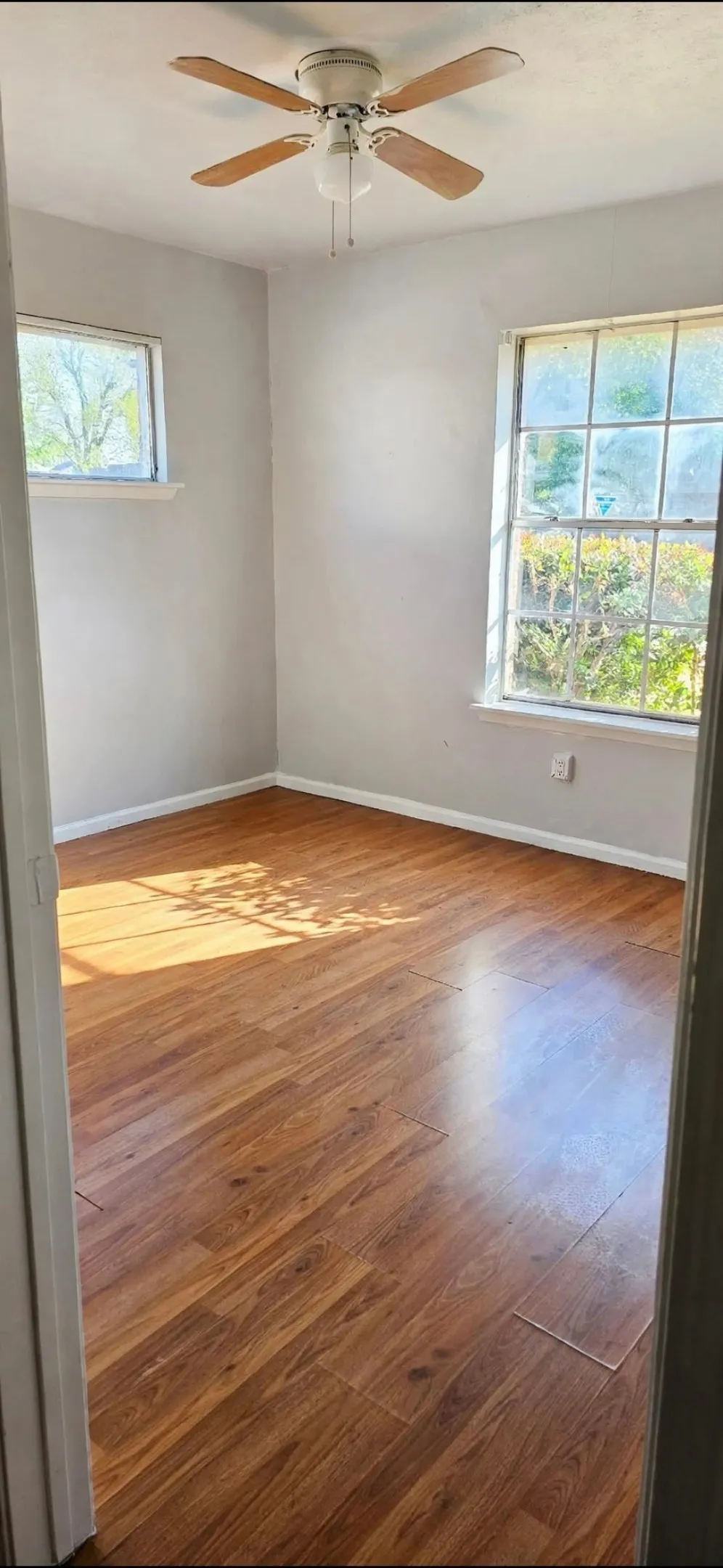 Bedroom3-Wood finish flooring with a ceiling fan and natural light from two windows