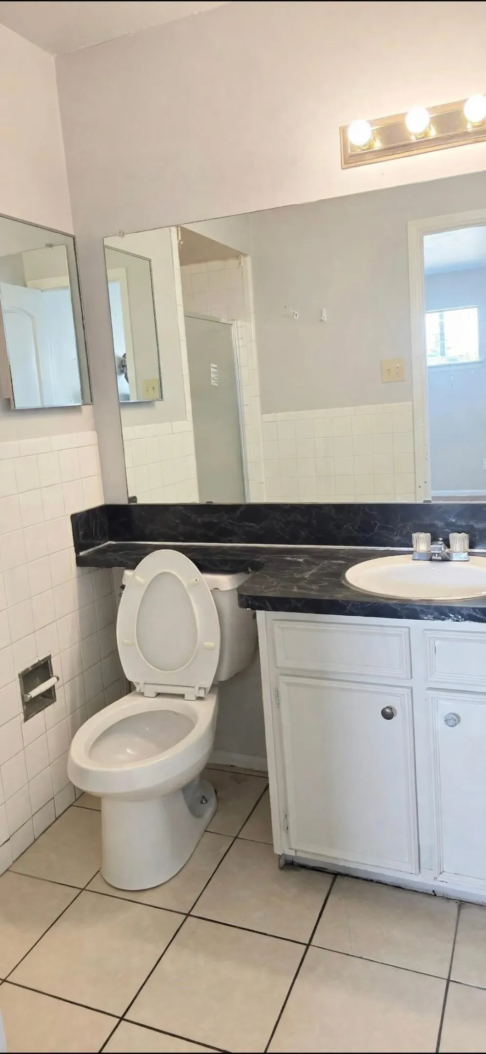 Bathroom featuring a white toilet, white vanity with integrated sink, dark countertop, and tiled flooring