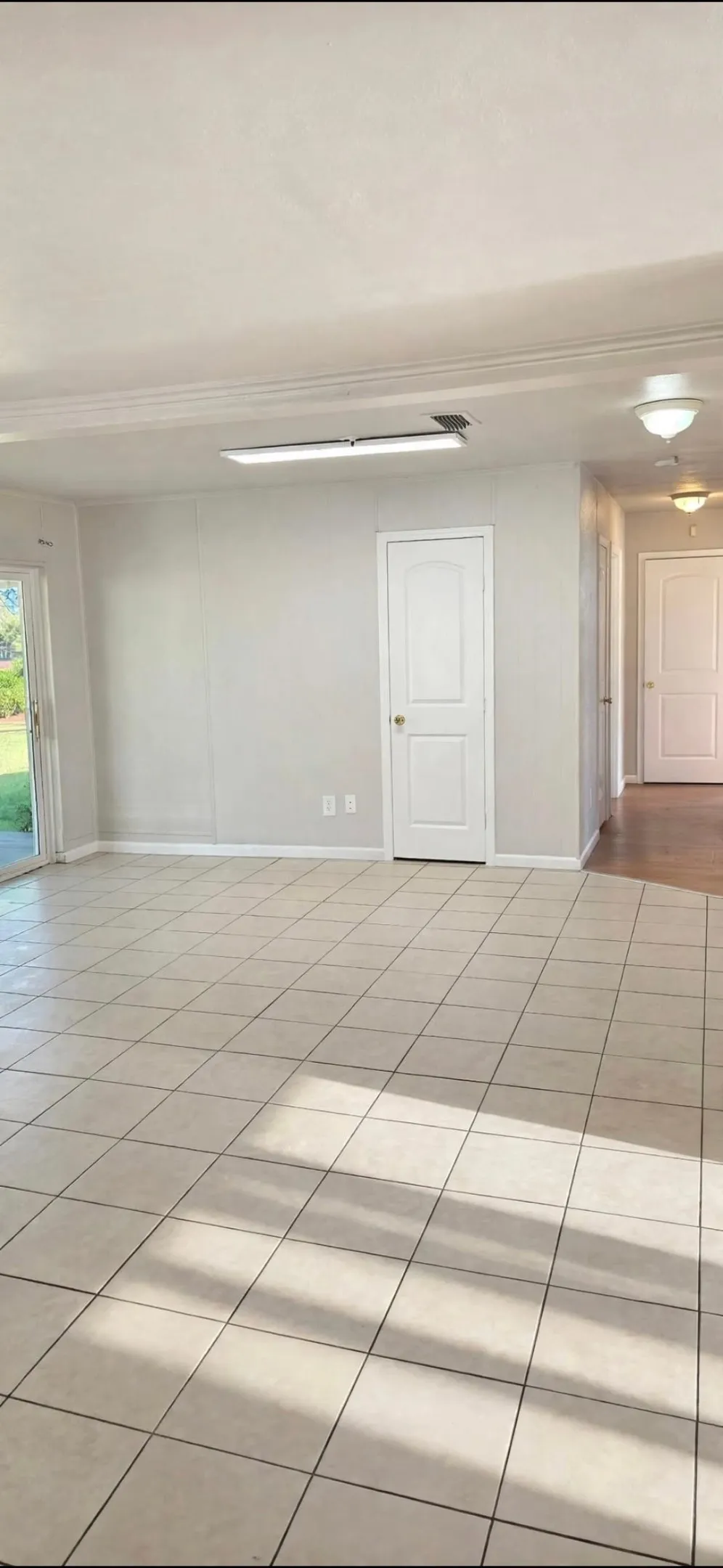 Neutral tone walls, square tile flooring, crown molding, two-panel interior doors, and a sliding glass door