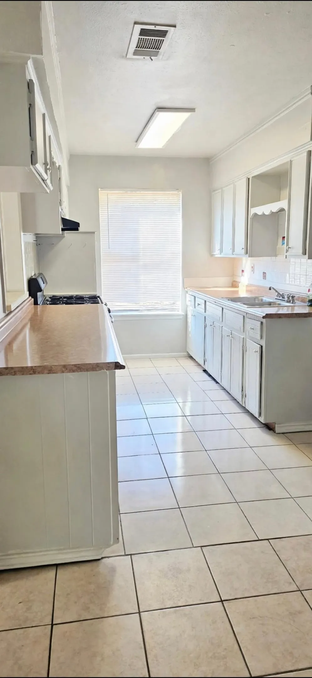 Galley kitchen featuring white cabinetry, light-toned countertops, and tile flooring