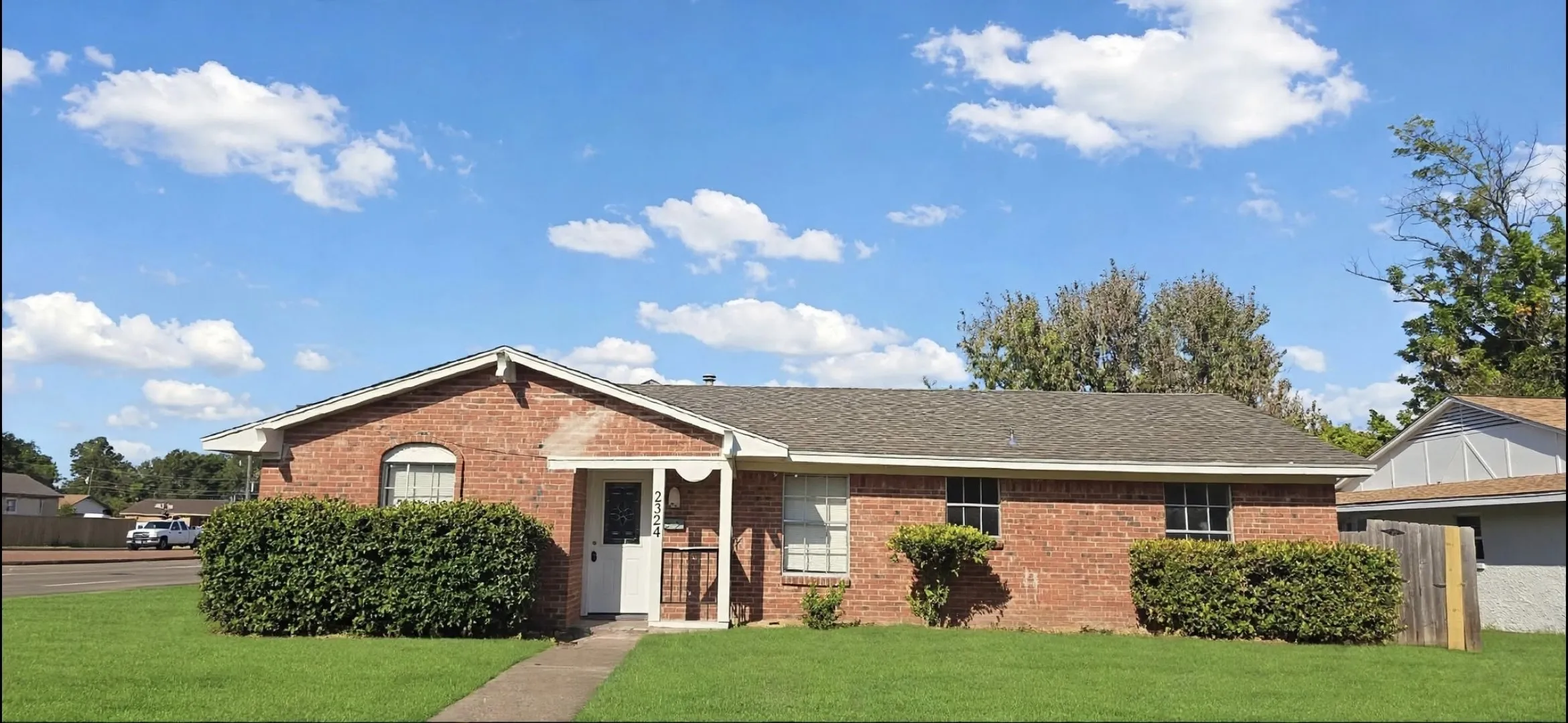 pic 2 Red brick exterior with a grey shingle roof, covered entry, and front landscaping