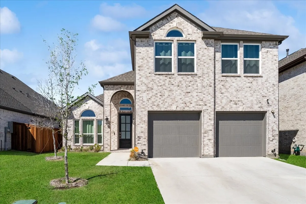 Two-story brick exterior with arched entryway, dual garage doors, and arched transom windows