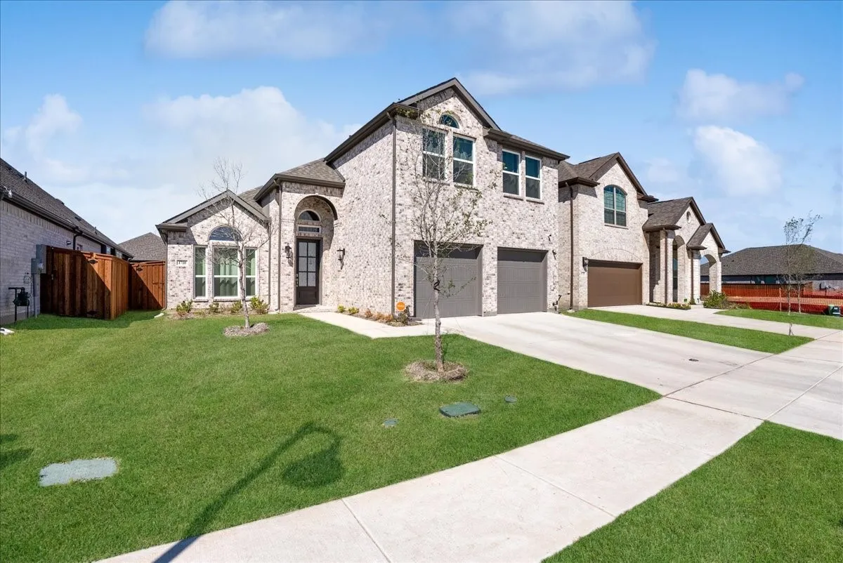 Brick facade with arched entryway, two-car garage, and concrete driveway