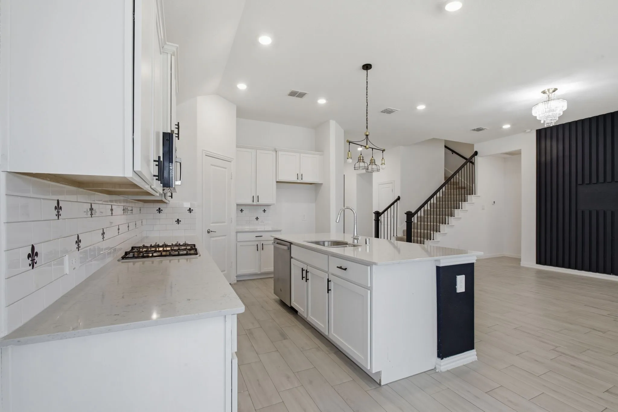 Spacious kitchen with light-toned countertops, white cabinetry, and an island featuring an undermount sink