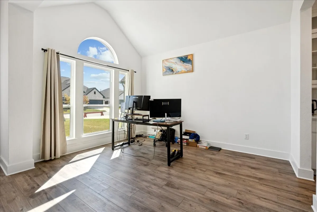 Vaulted ceiling with an arched window, large picture windows, wood-finish flooring, and bright white walls