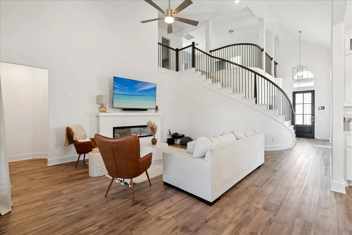 Expansive living area featuring wood-finish flooring, a contemporary fireplace, and a ceiling​​‌​​​​‌​​‌‌​‌‌​​​‌‌​‌​‌​‌​​​‌​​ fan