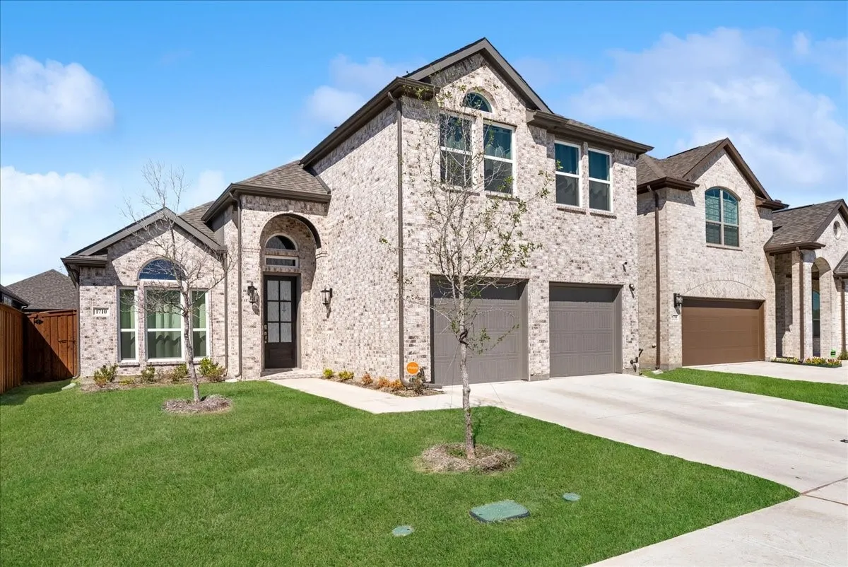 Brick exterior with arched entryways, multiple windows, and two garage doors