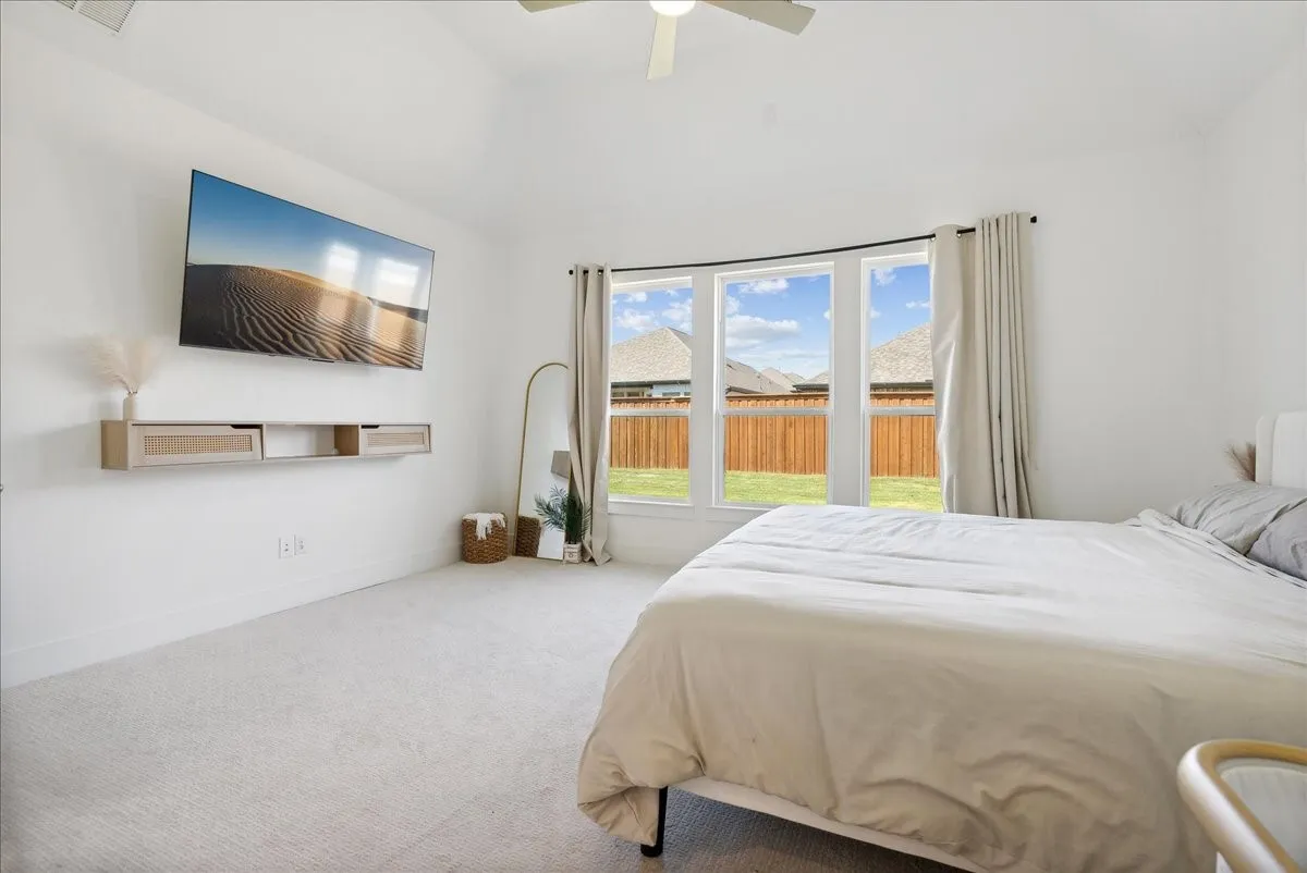 Recessed lighting, ceiling fan, white carpet, three large windows, and a floating wall-mounted console