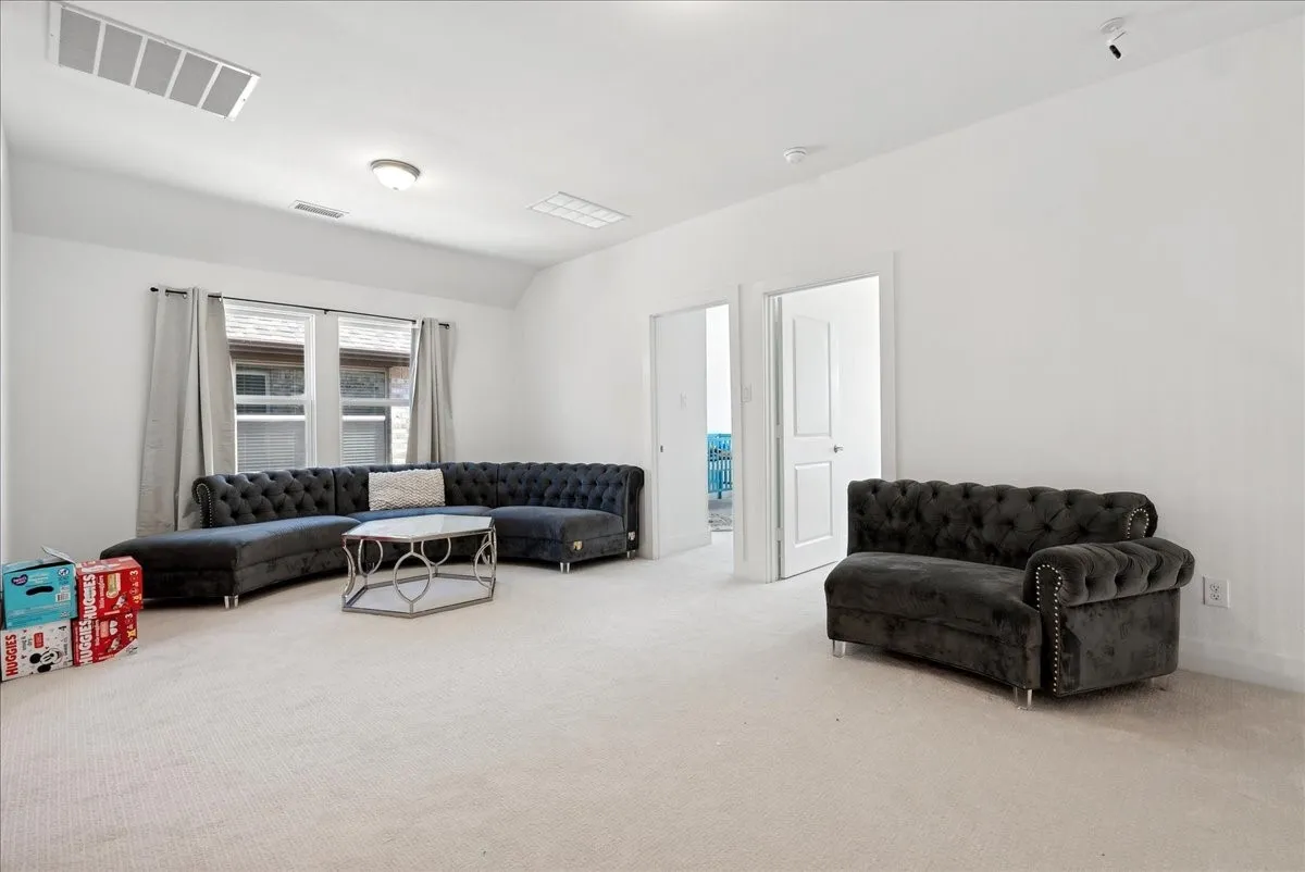 White walls with neutral carpet flooring, featuring multiple windows and two white interior doors