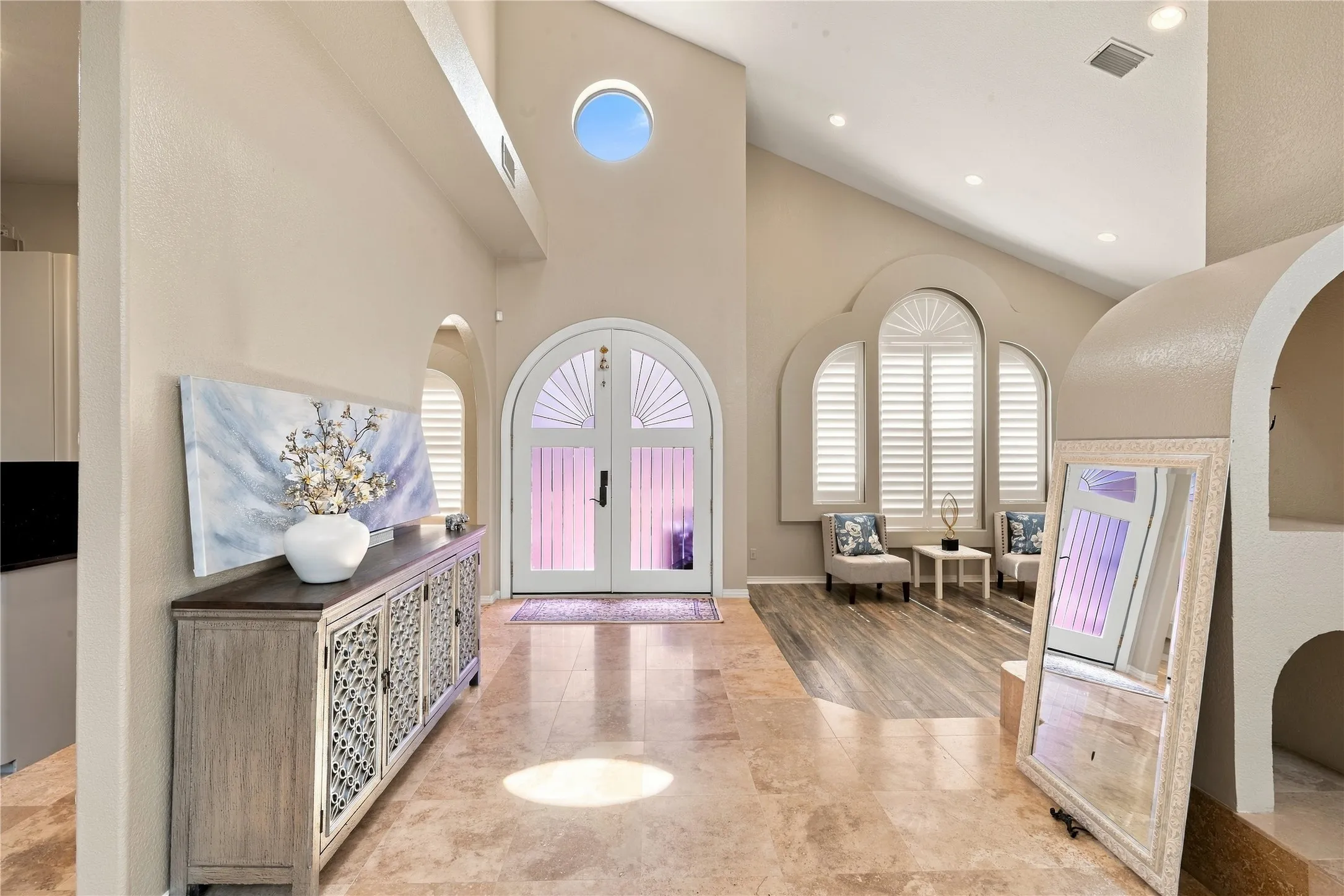 Bright, elegant foyer with soaring ceilings and distinctive arched details.
