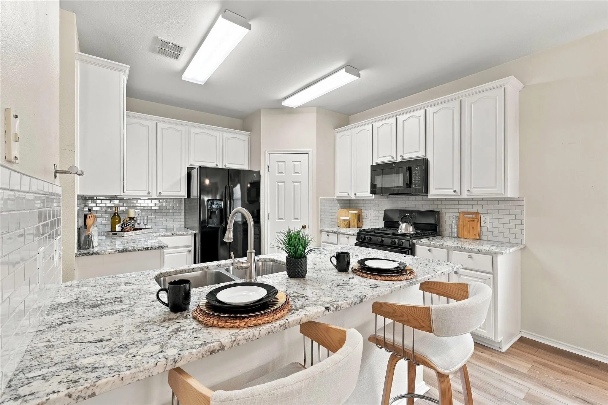 During the 2022 kitchen update, the bar was lowered to counter height, opening up the space and creating a great spot for bar stools. White cabinetry, granite countertops and a subway tile backsplash give the kitchen a fresh, modern and neutral feel.