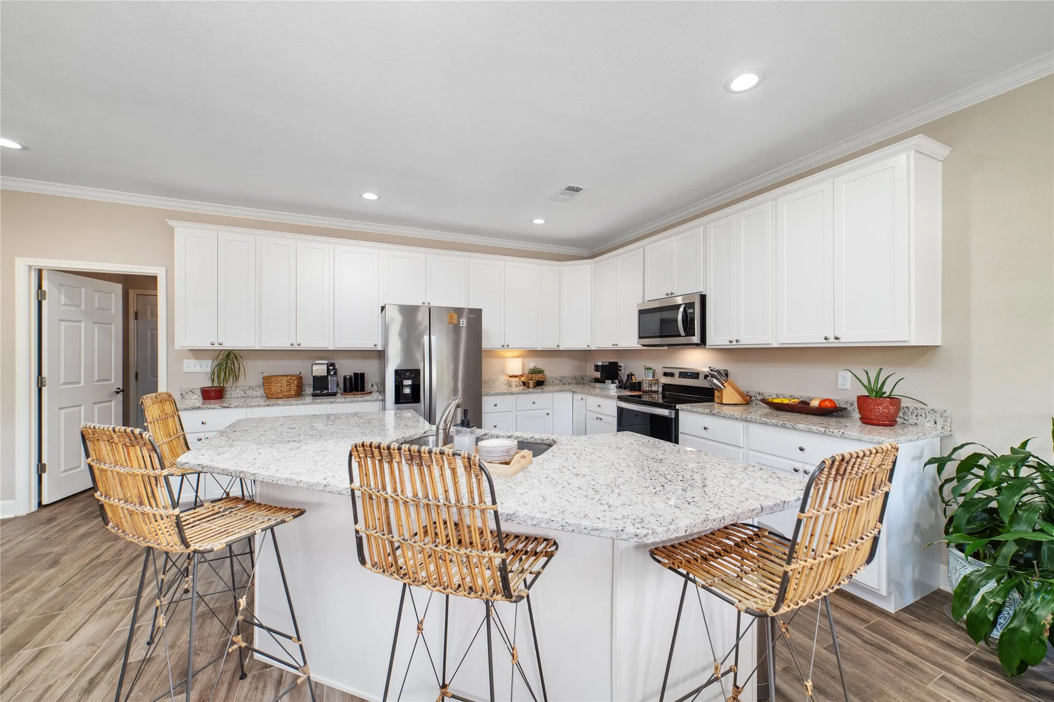 Kitchen featuring a breakfast bar, stainless steel appliances, light hardwood / wood-style floors, ornamental molding, and sink
