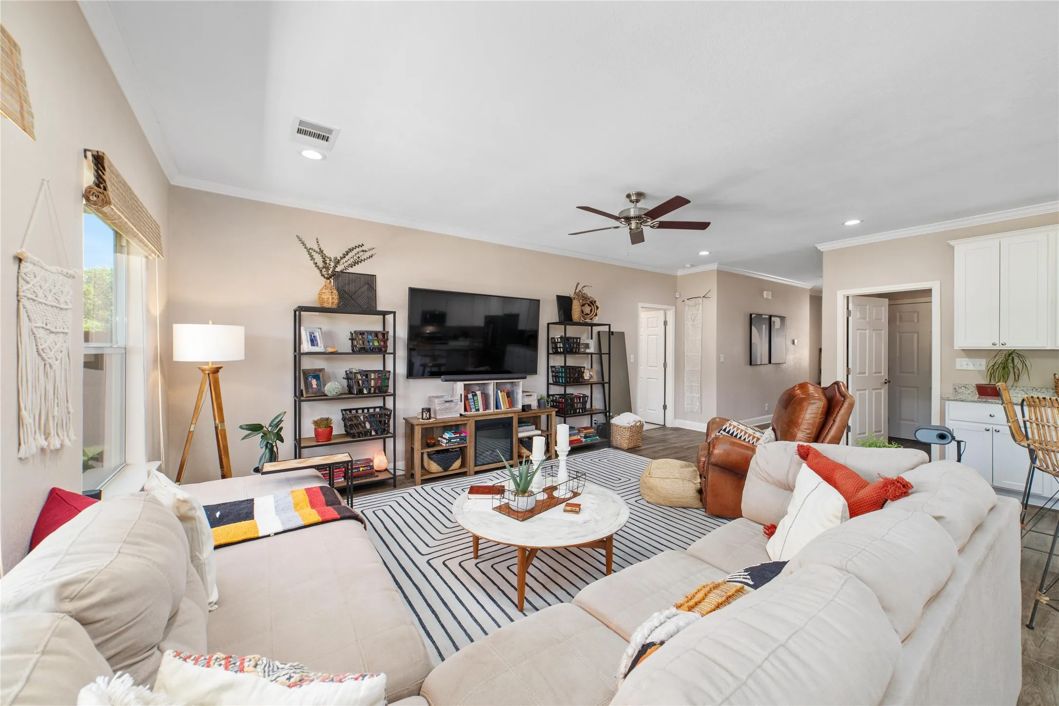 Living room with wood-type flooring, crown molding, and ceiling fan