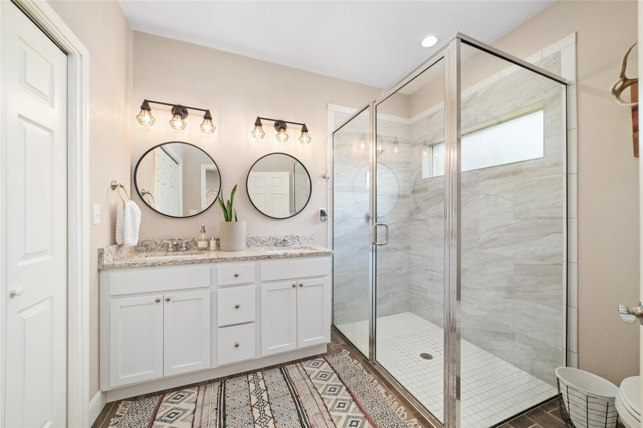 Bathroom featuring an enclosed shower and dual bowl vanity