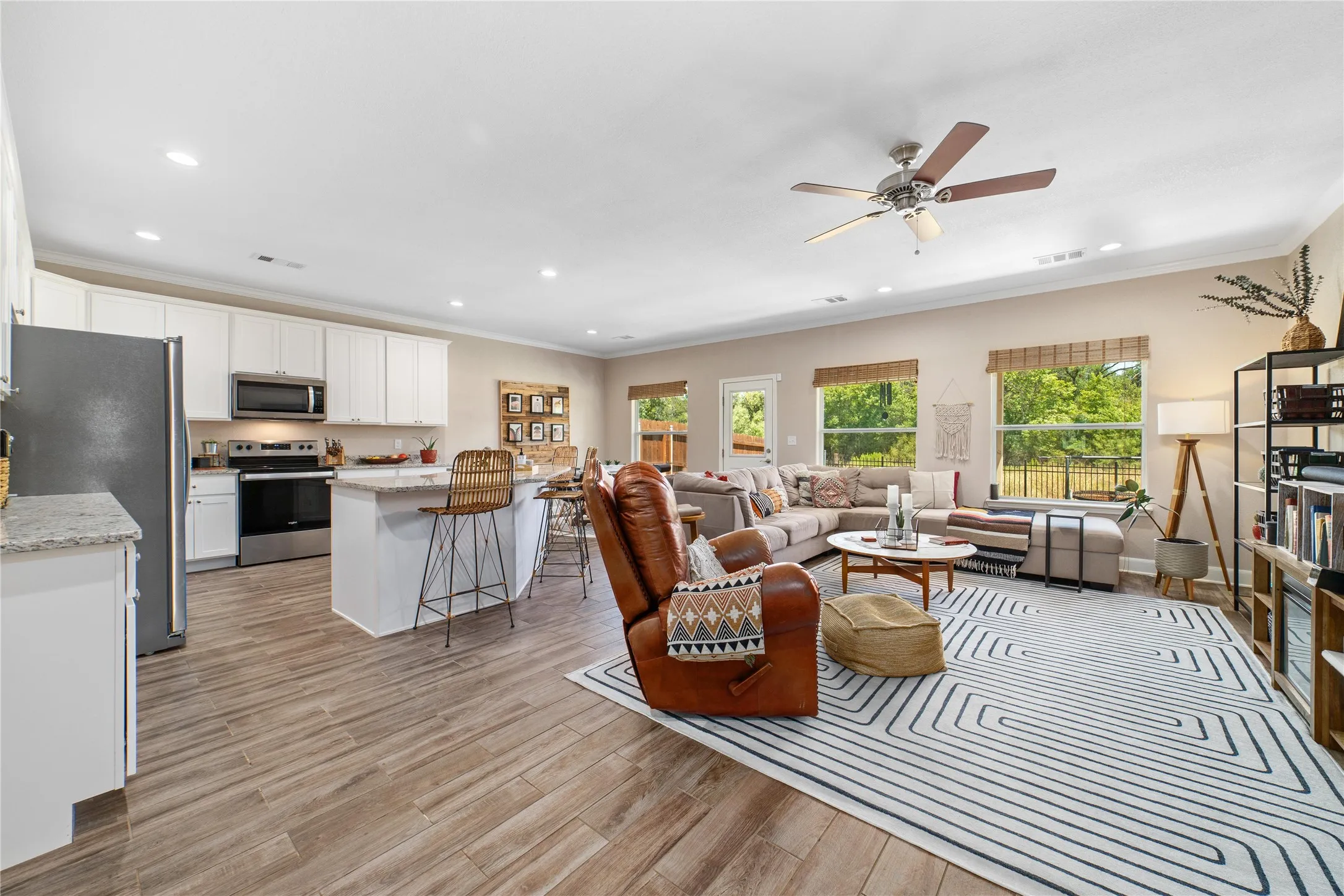 Living room with ceiling fan, crown molding, and light wood-type flooring