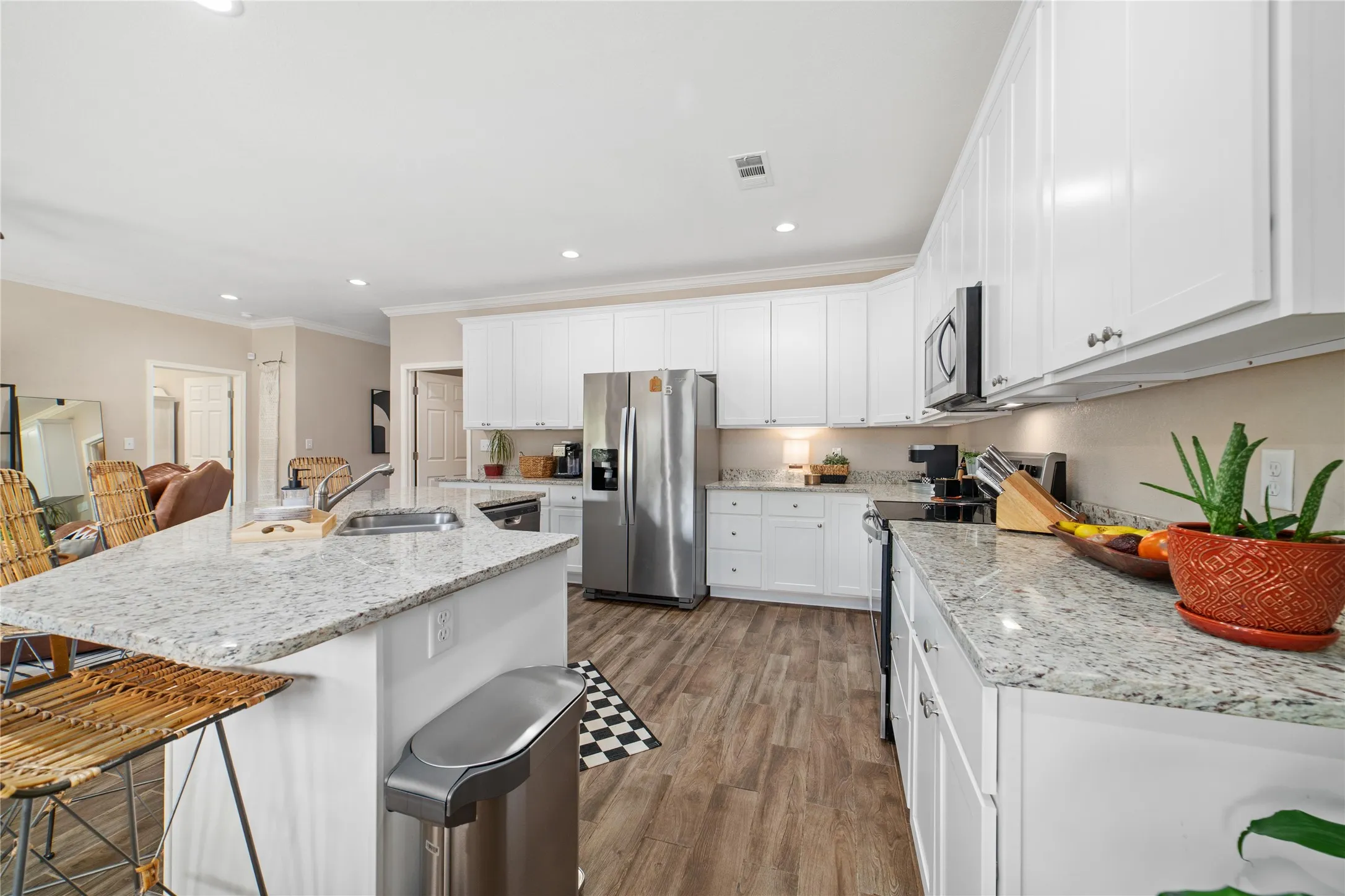 Kitchen with a kitchen island with sink, appliances with stainless steel finishes, a breakfast bar area, light wood-type flooring, and white cabinetry