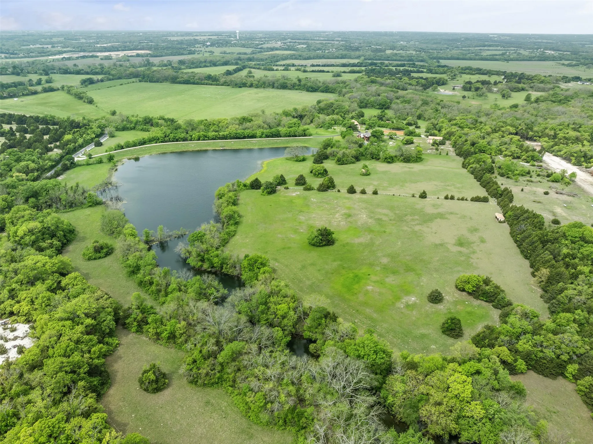 Expansive acreage featuring a private pond, abundant mature trees, and open green spaces