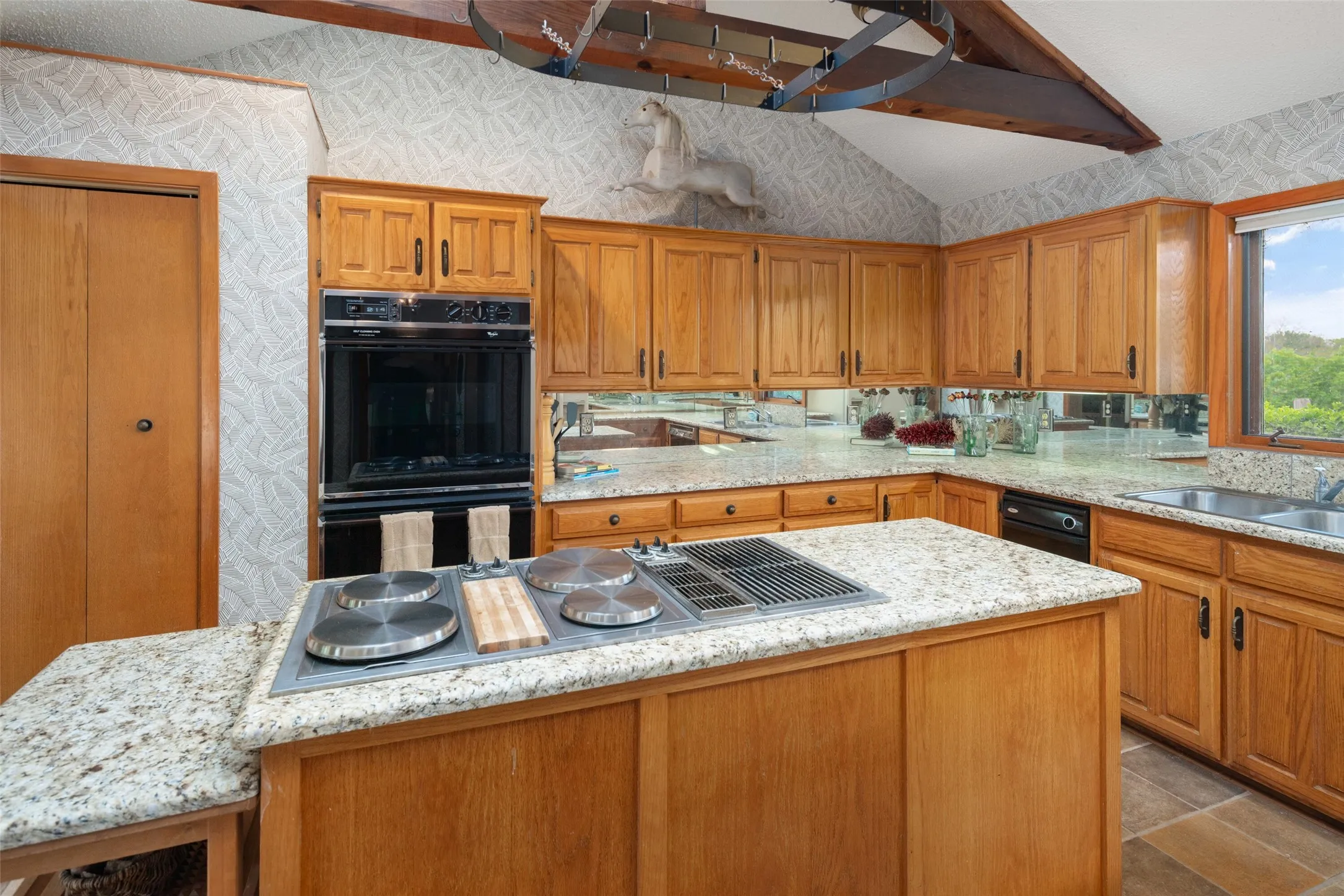 Wood cabinetry and granite countertops with a built-in oven and cooktop island