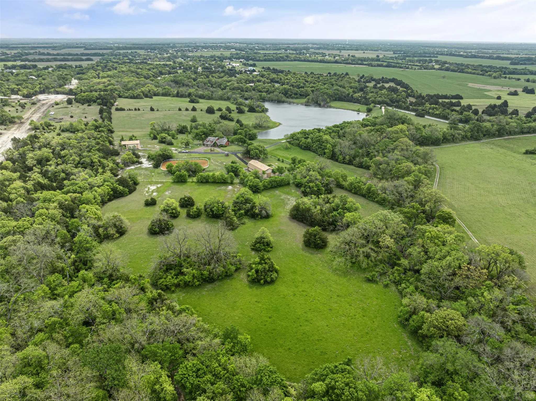 Expansive acreage featuring abundant mature trees, open grassy areas, and a visible body of water