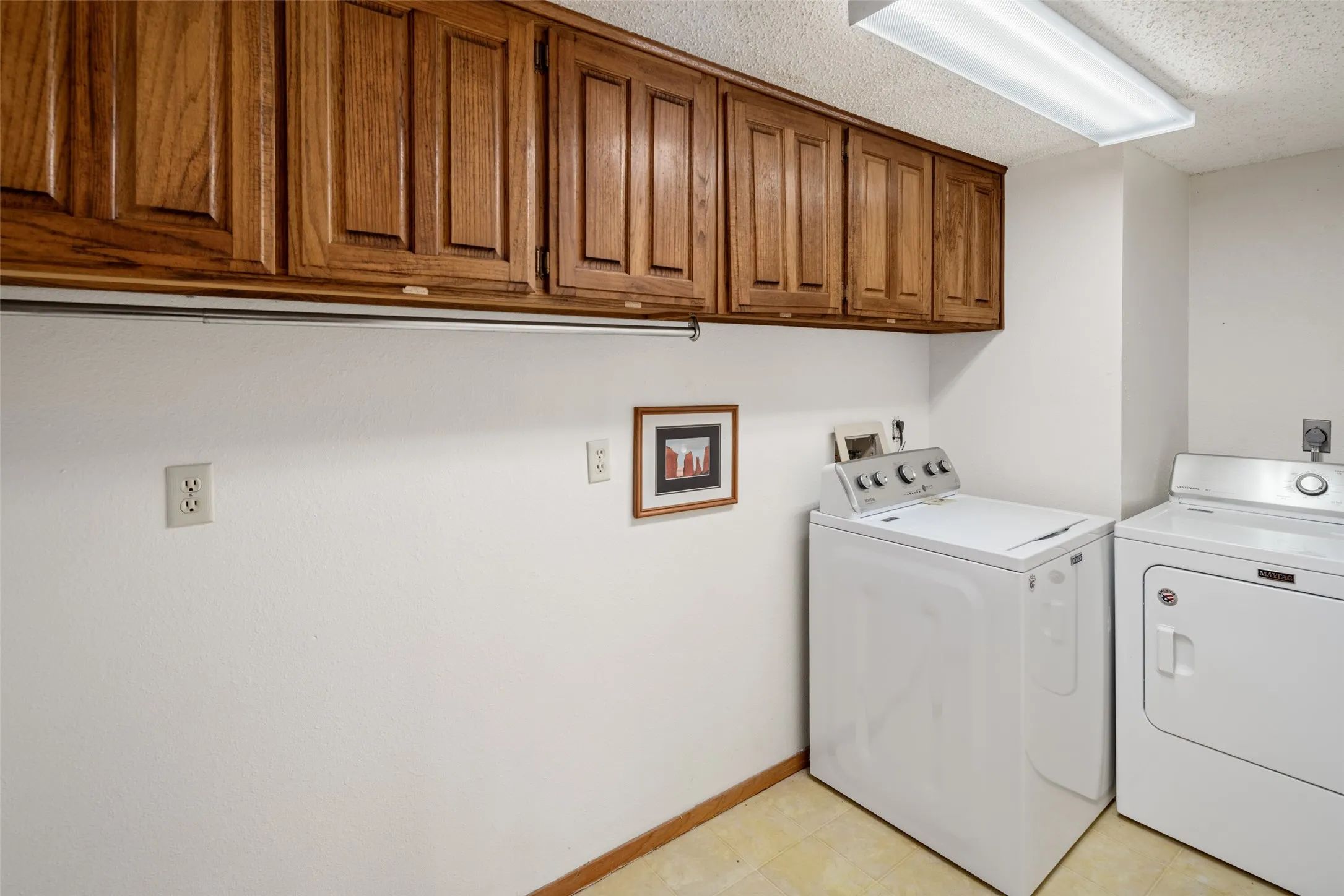 Wood-finish upper cabinetry, fluorescent ceiling light fixture, and wood-finish trim