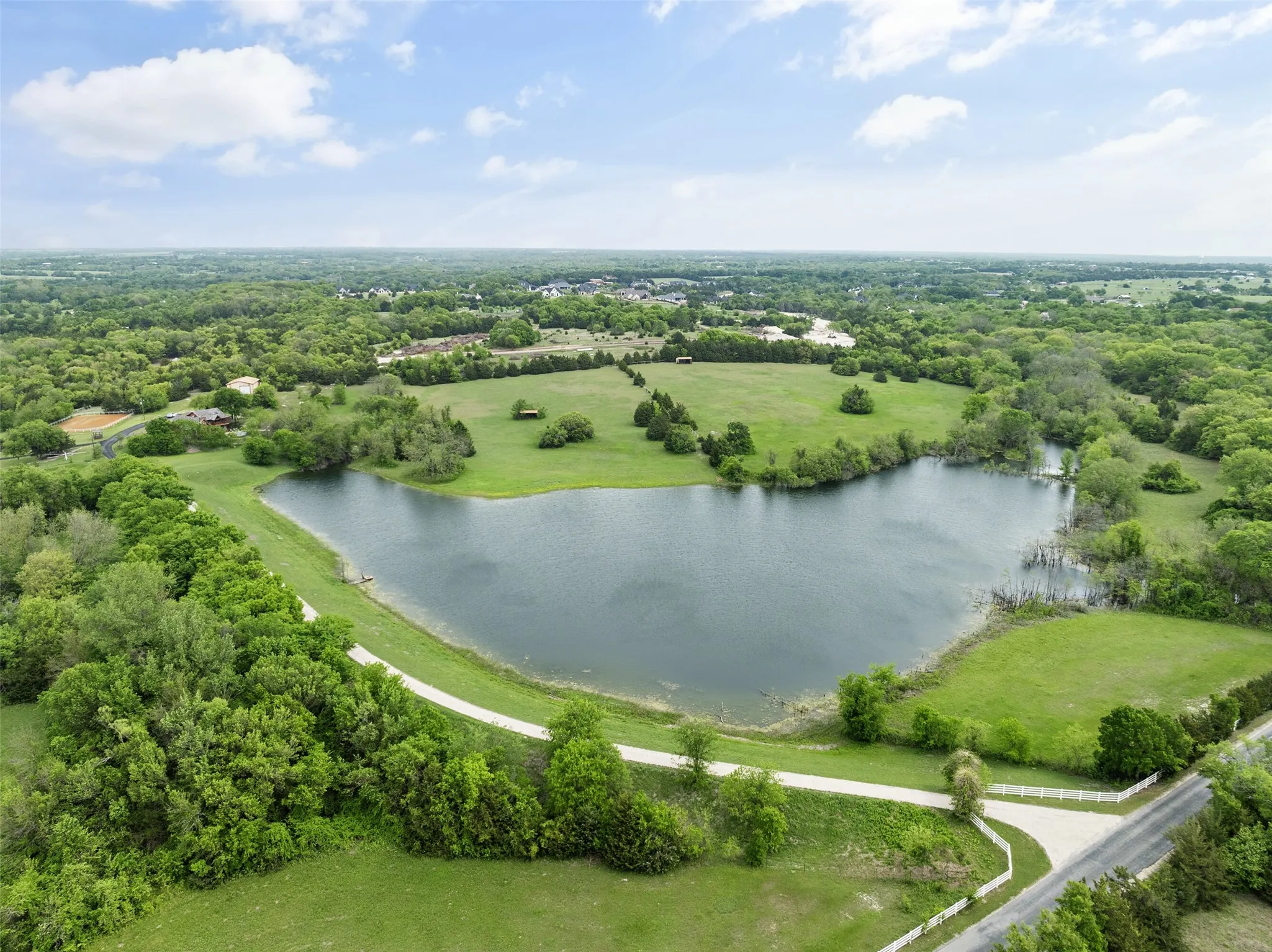 Lush, expansive grounds featuring a private lake surrounded by mature trees and verdant fields