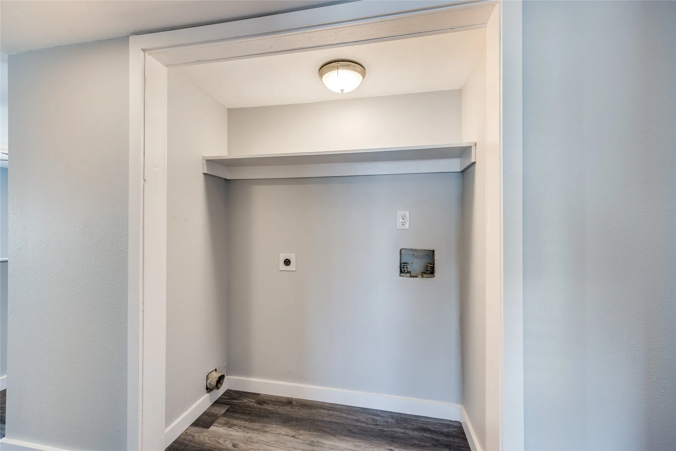 Dedicated utility alcove featuring wood-finish flooring, built-in shelving, and a flush mount ceiling light fixture