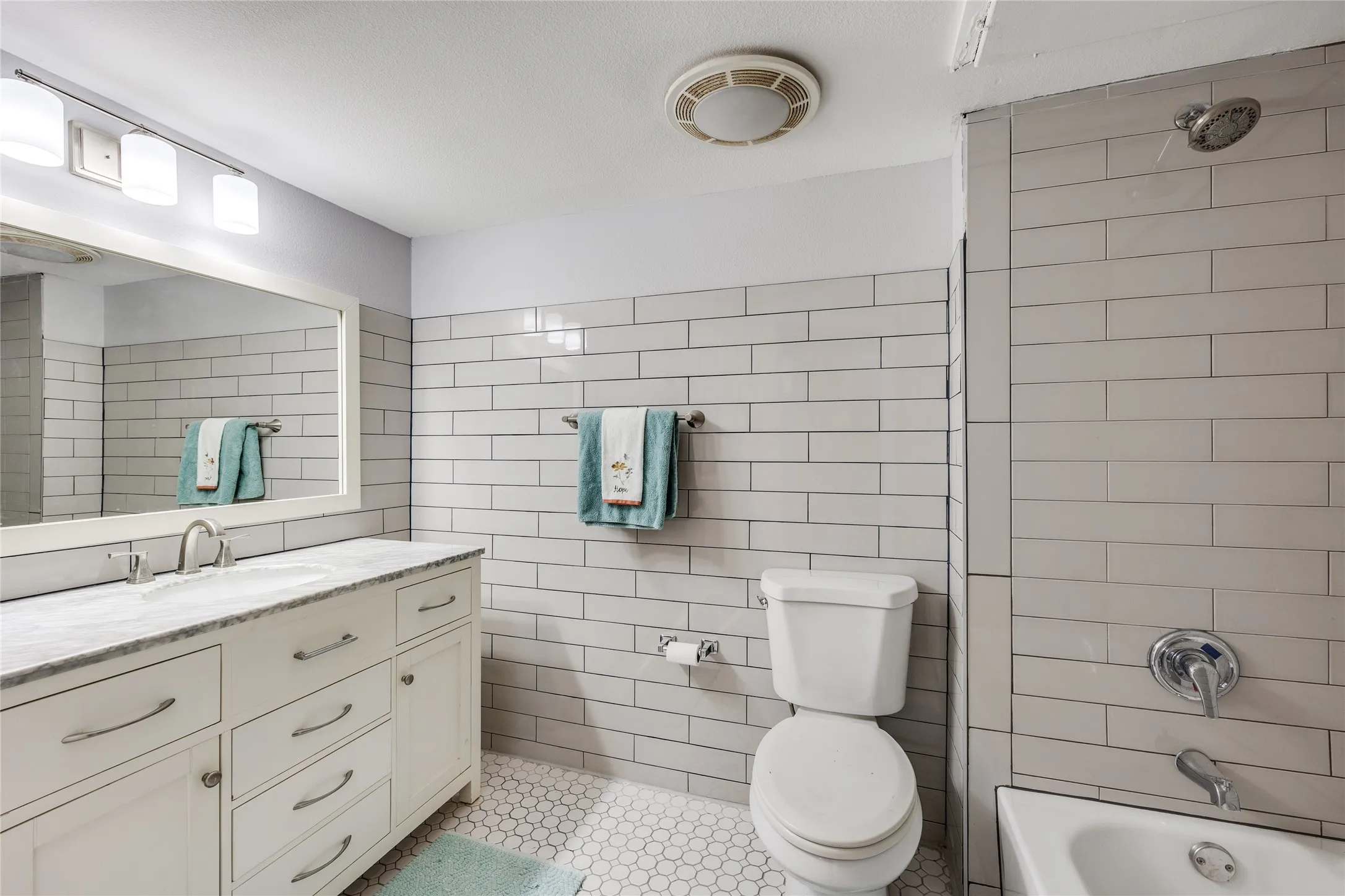 White vanity with an integrated sink and brushed nickel hardware, set against a subway-tiled wall