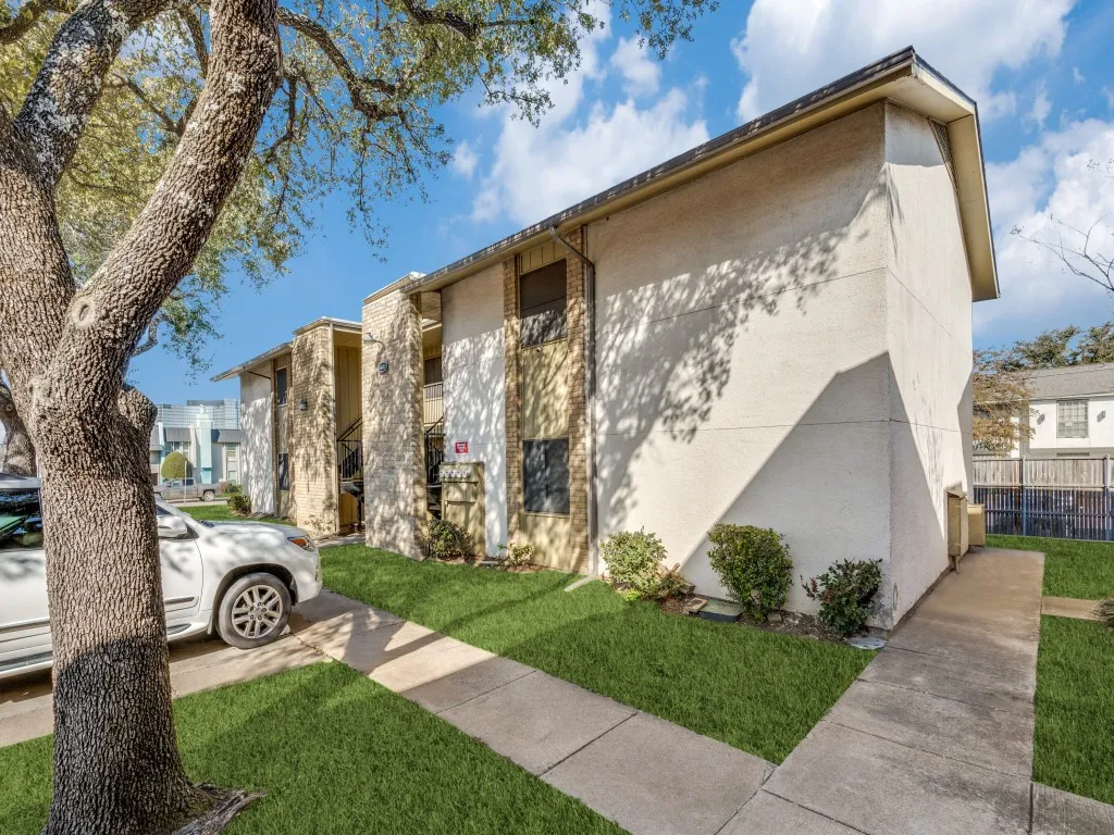 Two-story building with textured stucco exterior and brick accents