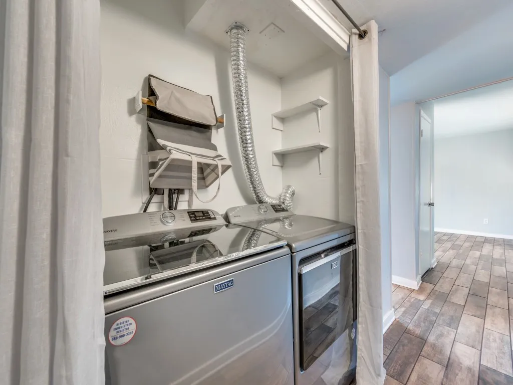 Laundry area with white walls and wood-finish flooring, featuring two wall-mounted shelves