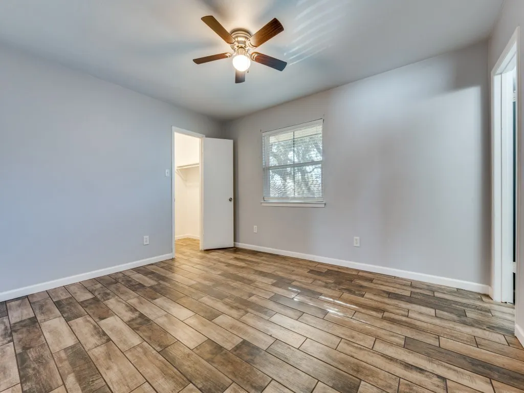 Wood-finish flooring, ceiling fan with integrated lighting, single window, and a built-in closet with shelving