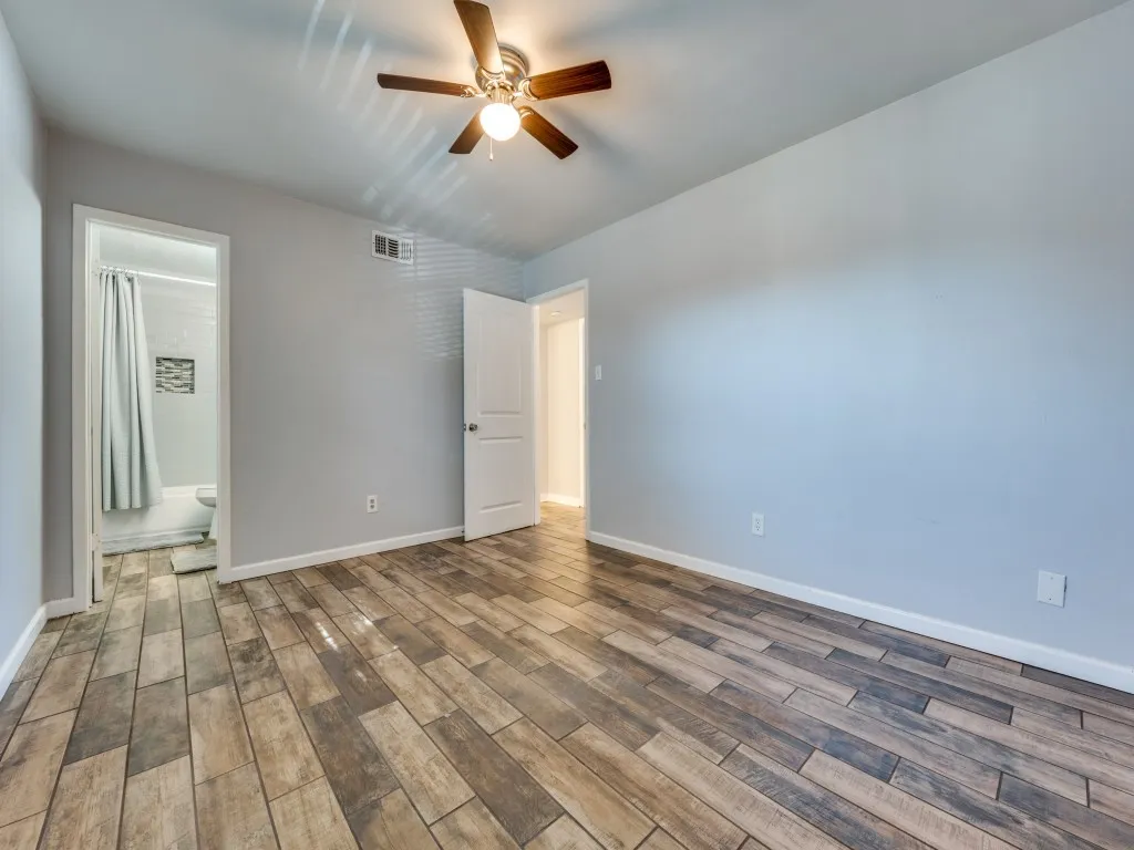 Wood-look tile flooring throughout, ceiling fan with integrated lighting, and light gray wall paint
