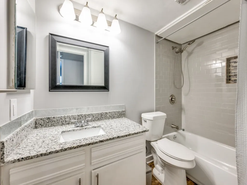 Vanity with granite-style countertop, undermount sink, and white cabinetry