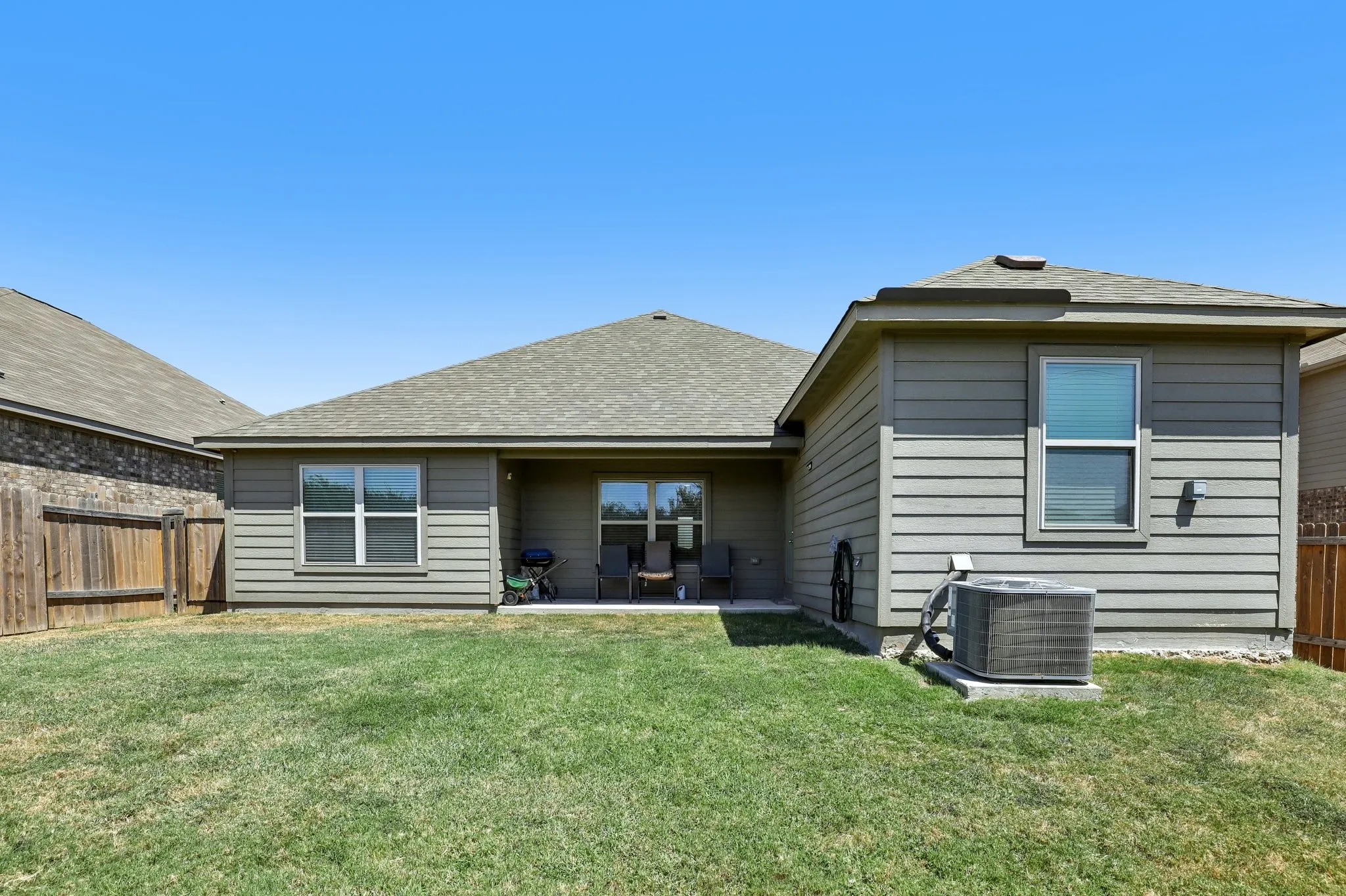Expansive lawn space, private wood fencing, and a covered patio area