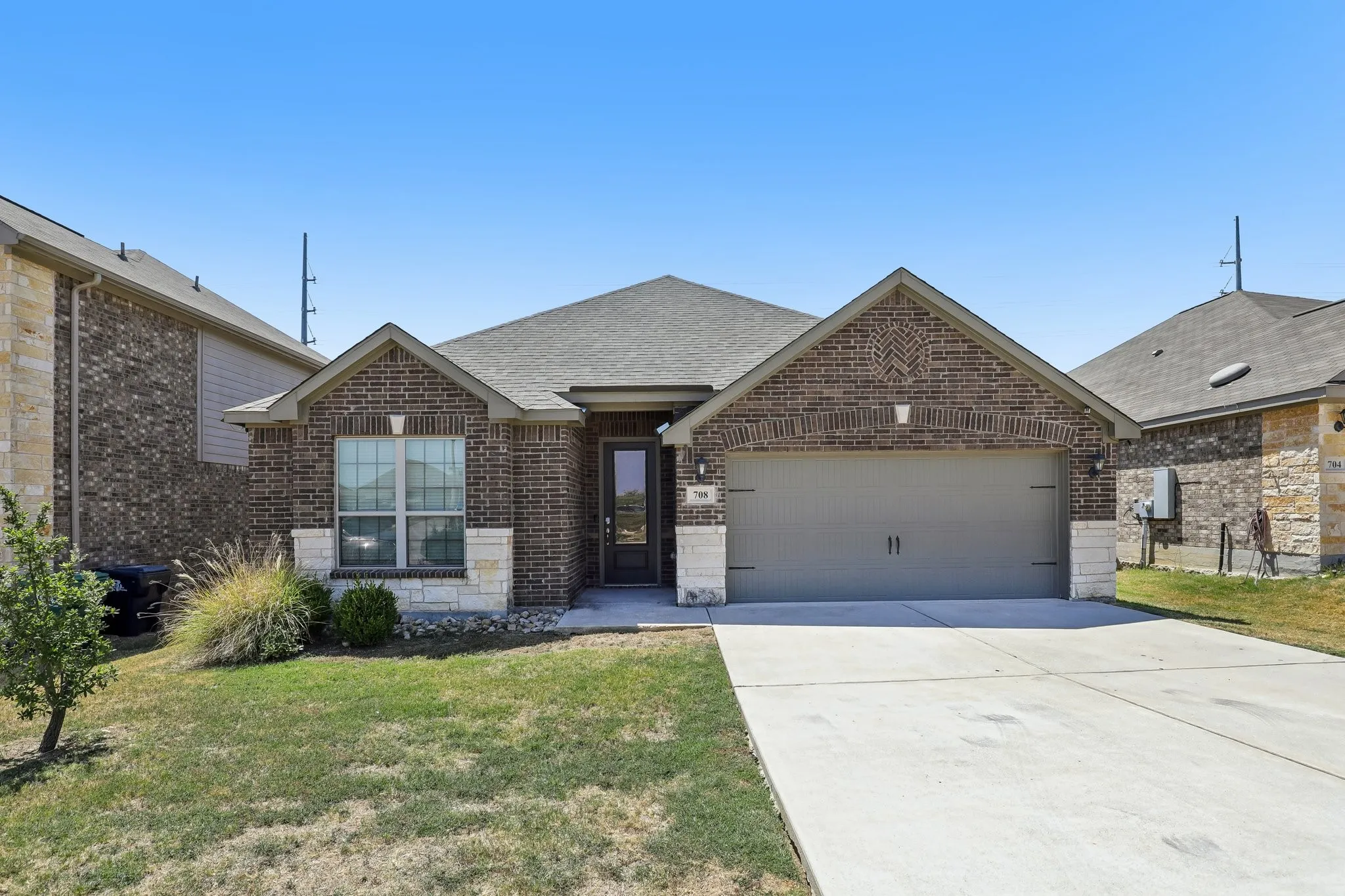Brick and stone veneer exterior with a gabled roofline, attached two-car garage, and a concrete driveway