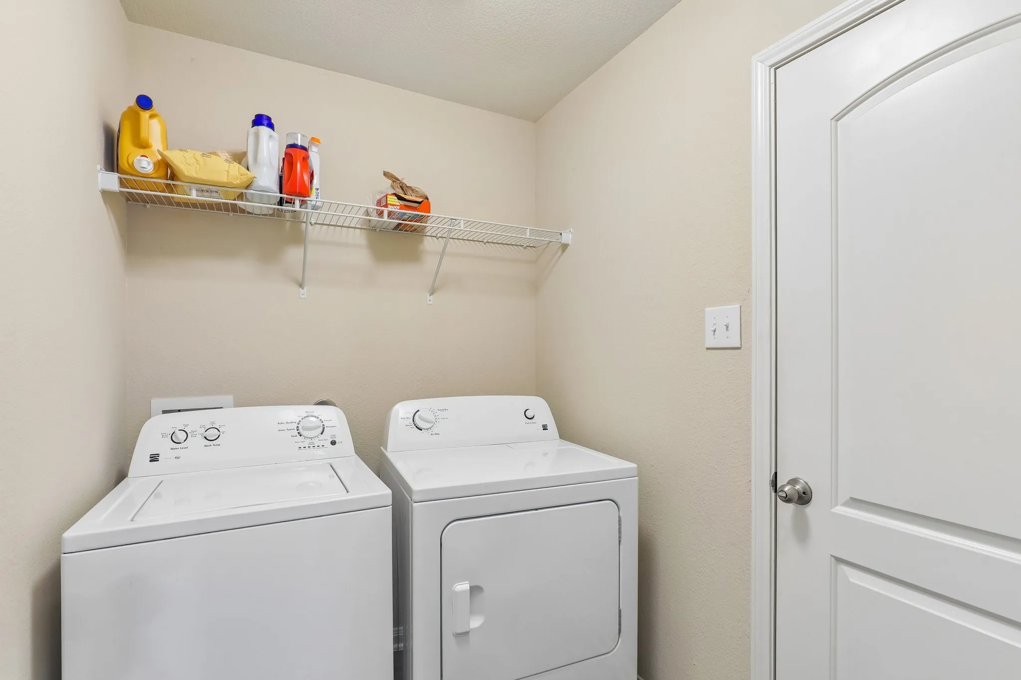 Laundry area featuring a wire storage shelf and a paneled door