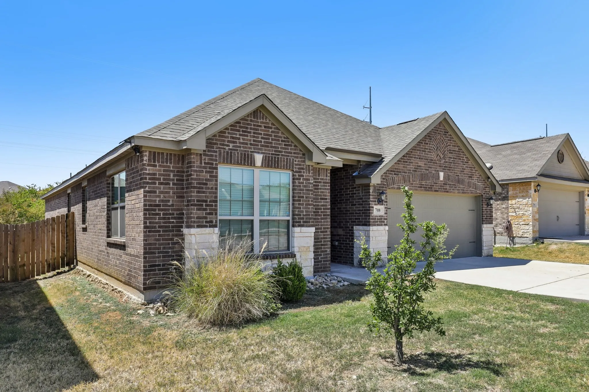 Brick exterior with stone accents, an attached garage, and a fenced side yard