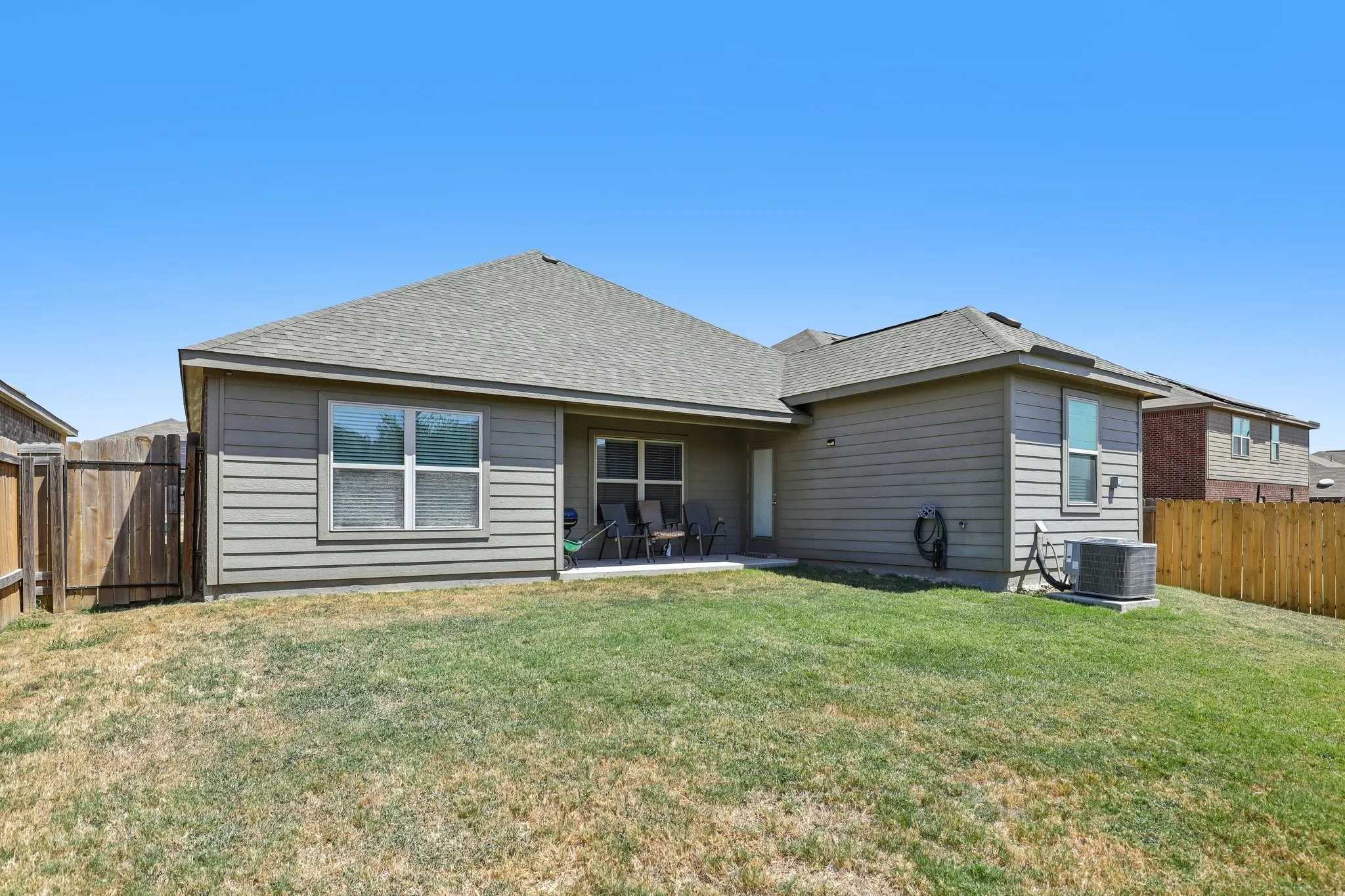 Expansive backyard featuring a concrete patio, horizontal siding exterior, and wood fencing