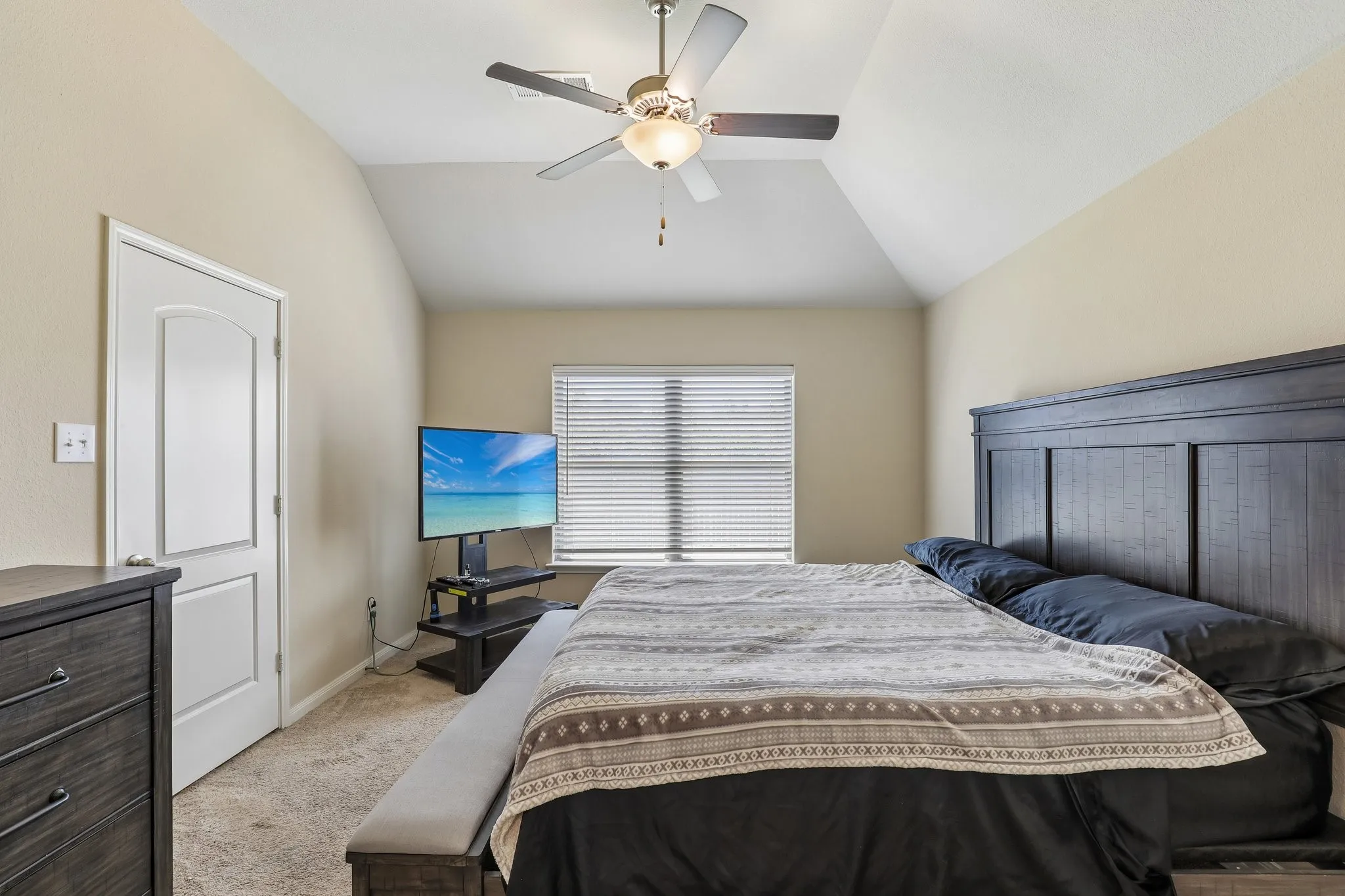 Vaulted ceiling with a ceiling fan, carpet flooring, and a window with horizontal blinds