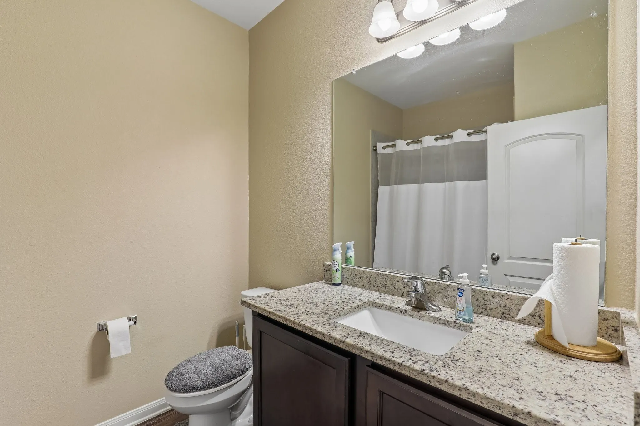Vanity with integrated sink, speckled countertop, and dark wood-finish cabinetry