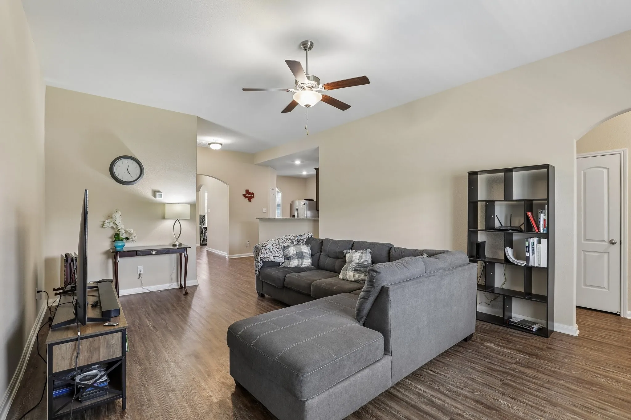 Living area featuring wood-finish flooring, a ceiling fan, and arched doorways