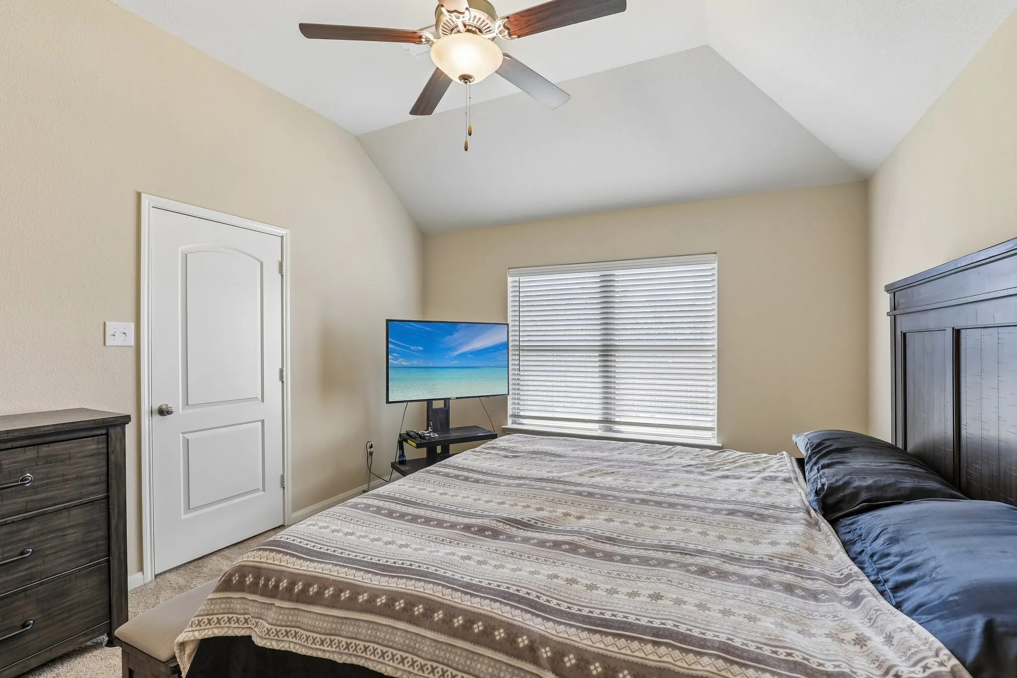 Vaulted ceiling with a ceiling fan, window with blinds, and white paneled door