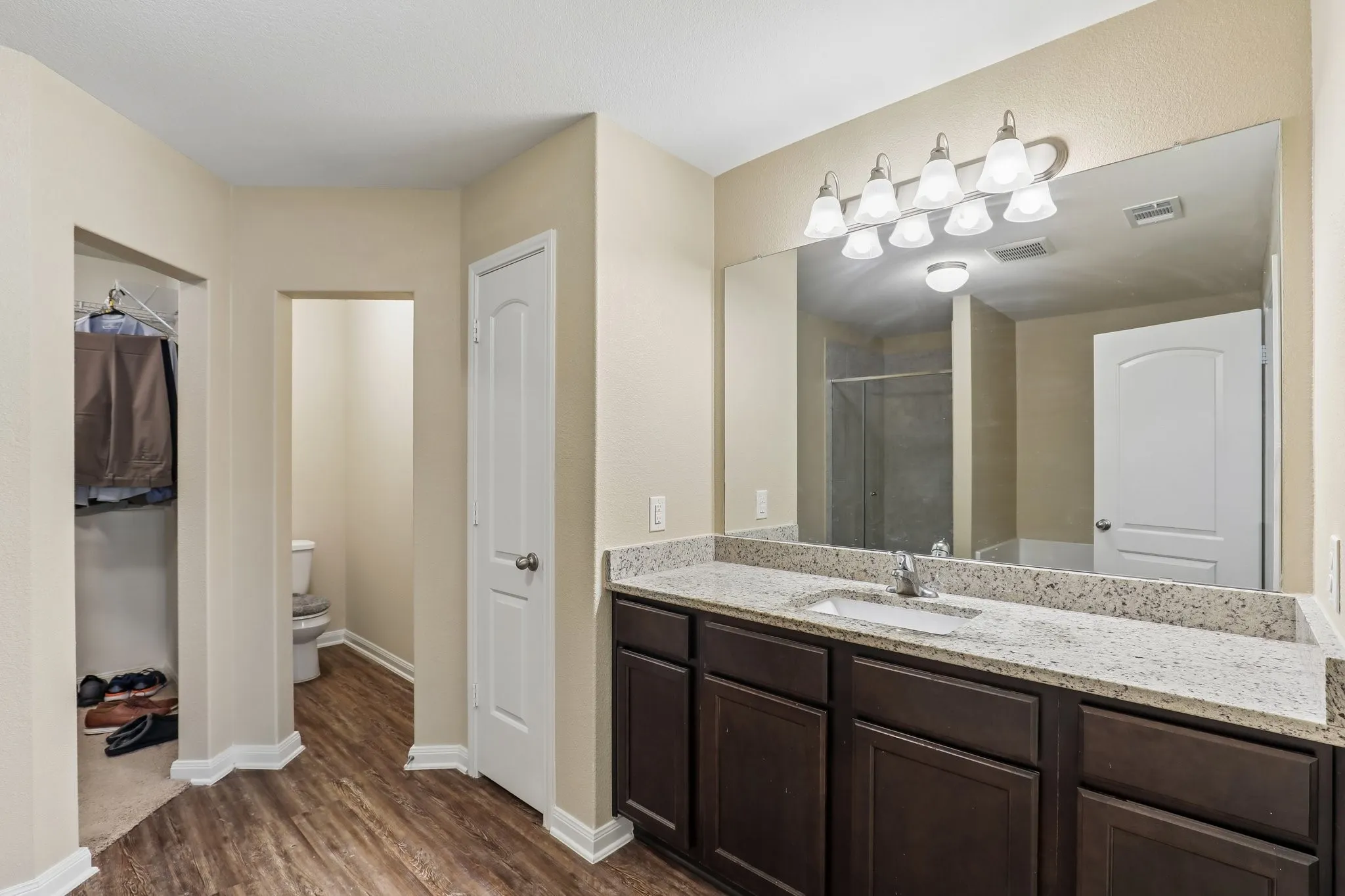 Wood-finish flooring throughout, a vanity with a light-colored countertop, and a built-in basin